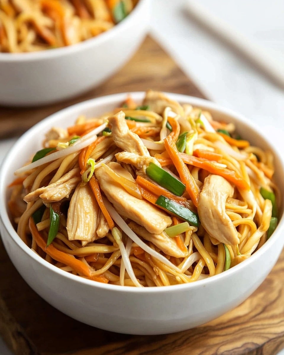A close-up view of a white bowl filled with stir-fried noodles, layered with light brown strips of cooked chicken, thin orange carrot slices, pale bean sprouts, and fresh green scallion pieces mixed well throughout. The bowl is placed on a wooden board, which rests on a white marbled surface. In the background, there is a second white bowl holding the same noodle dish, slightly out of focus. The colors show a warm and fresh combination of orange, green, light brown, and pale yellows. photo taken with an iphone --ar 4:5 --v 6.1