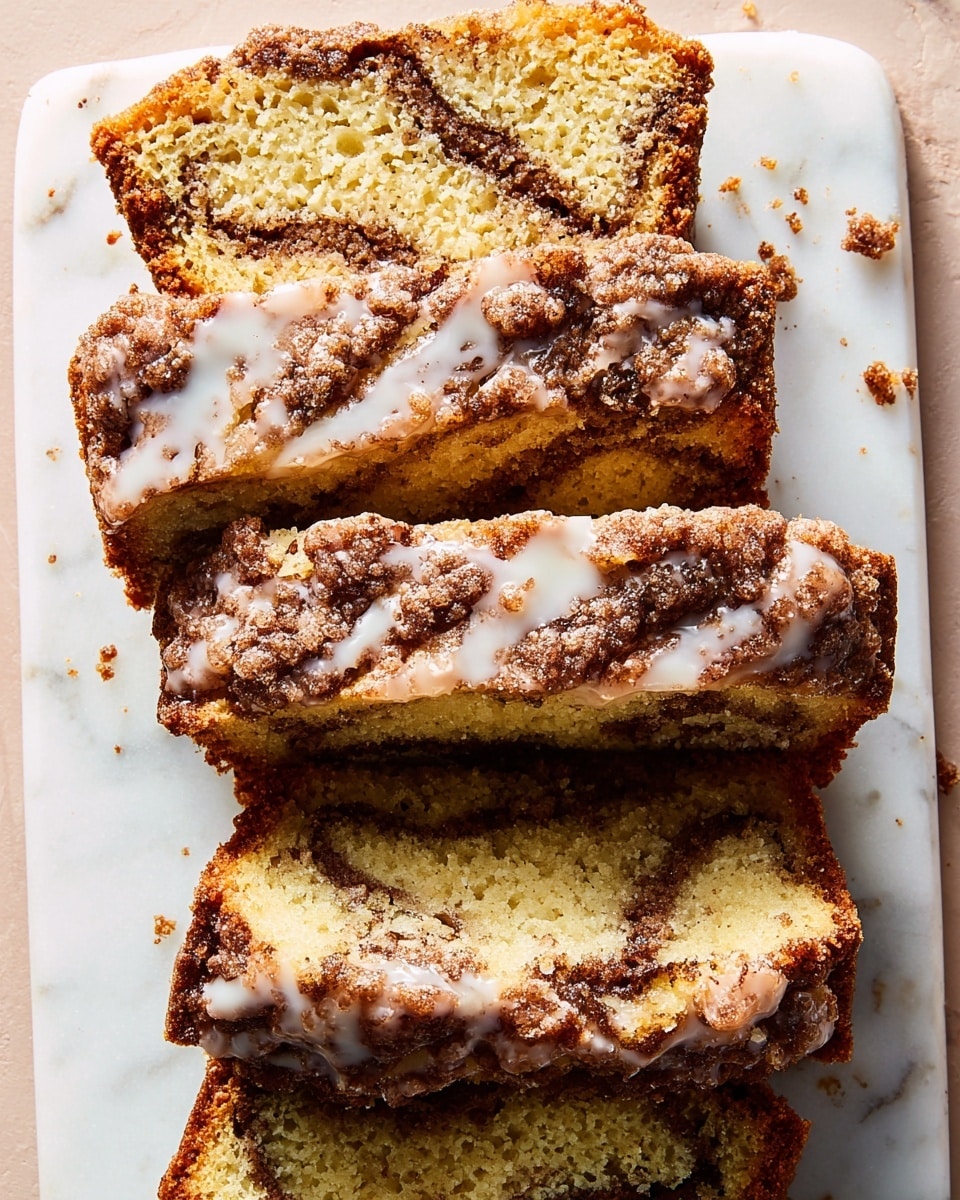 A loaf of cinnamon swirl cake is placed on a white marbled surface with two thick slices cut and laid next to it. The top layer of the cake has a dark brown crust with a rough texture, drizzled with white icing in an irregular pattern. Each slice reveals a moist, yellowish cake with visible darker brown cinnamon swirls running through the inside. Some crumbs are scattered near the slices and the cake, adding to the fresh baked look. Photo taken with an iphone --ar 4:5 --v 7