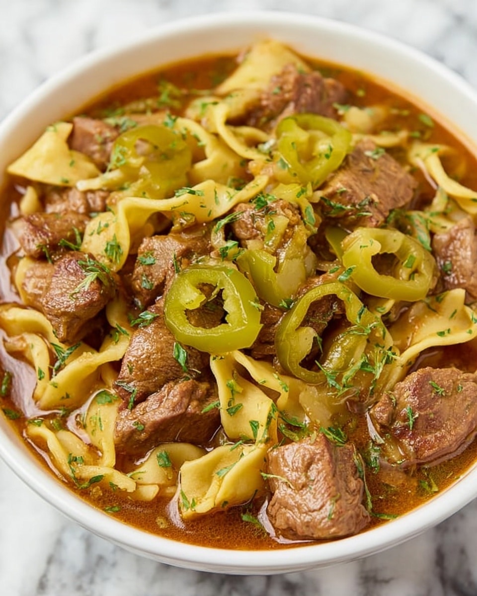 A white bowl filled with a layered stew featuring large chunks of brown meat scattered throughout, mixed with flat, wide noodle pieces that have a light yellow color and soft texture. Bright green sliced peppers are placed on top, adding a pop of color against the brown broth, which looks rich and slightly thick. Small flecks of green herbs are sprinkled all over the dish. The bowl sits on a white marbled surface. Photo taken with an iphone --ar 4:5 --v 7