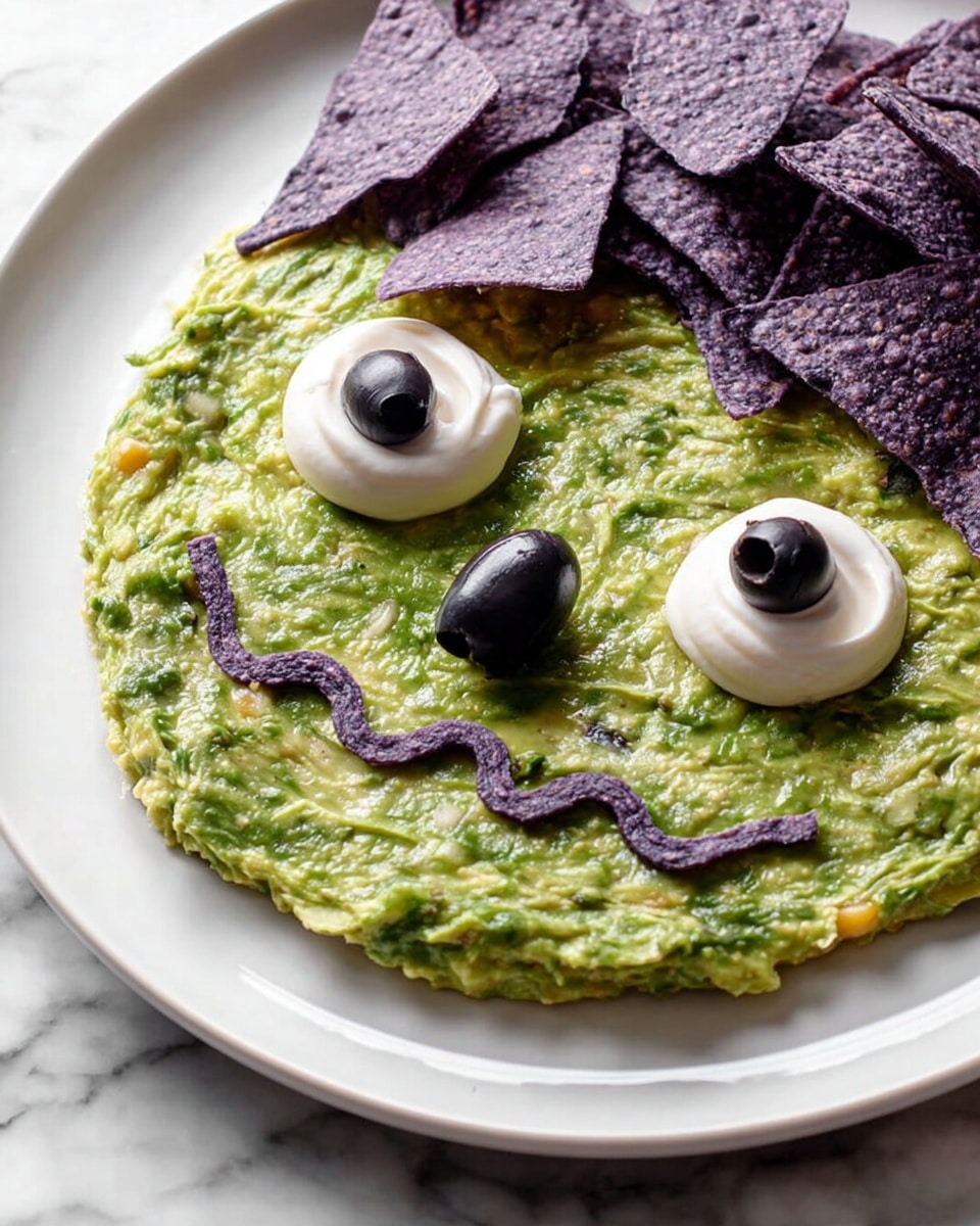 The image shows a white plate with a spread of green guacamole as the base layer, smooth with some texture from small bits of ingredients. On the guacamole, two dollops of white sour cream with black olive slices are placed as eyes, with a whole black olive acting as the nose between them. A wavy line made from refried beans forms a smiling mouth on the guacamole. On the upper right side of the plate, there is a pile of purple corn tortilla chips resting on the white plate. The plate is set on a white marbled surface. photo taken with an iphone --ar 4:5 --v 7