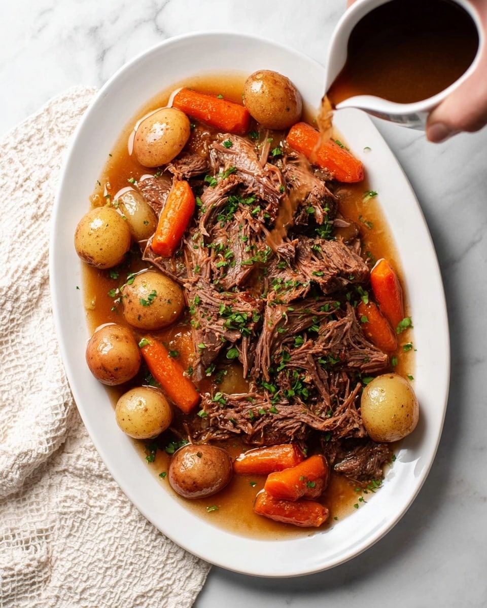 The image shows a white oval plate filled with layers of shredded brown meat on top of small whole brown potatoes and orange baby carrots, all mixed in light brown broth. The dish is sprinkled with small green herb pieces, adding a pop of color. A woman's hand is pouring dark brown gravy from a small white pitcher over the food. The plate is placed on a white marbled surface with a white and beige textured cloth beside it. photo taken with an iphone --ar 4:5 --v 7