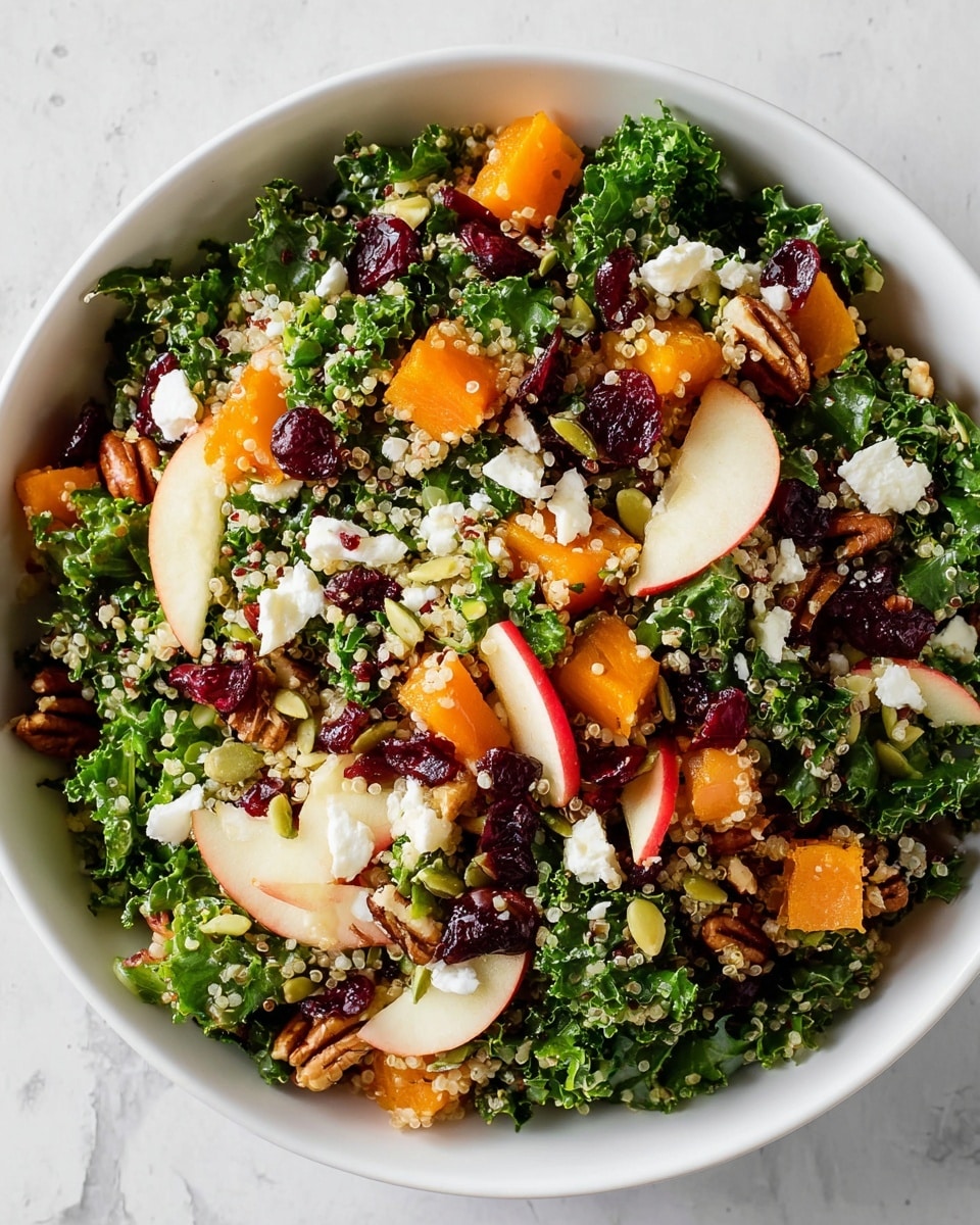 Two white bowls are filled with layered salad on a white marbled surface. The bottom layer is made of dark green curly kale leaves, scattered with light beige quinoa grains. On top, there are small chunks of orange butternut squash, red apple slices with skin, and deep red dried cranberries. White crumbled cheese and brown pecan halves are spread across for texture. Green pumpkin seeds are sprinkled over everything, adding small shiny spots. Around the bowls, there are small white dishes holding dried cranberries and pumpkin seeds, and a small jar with light yellow dressing. Photo taken with an iphone --ar 4:5 --v 7