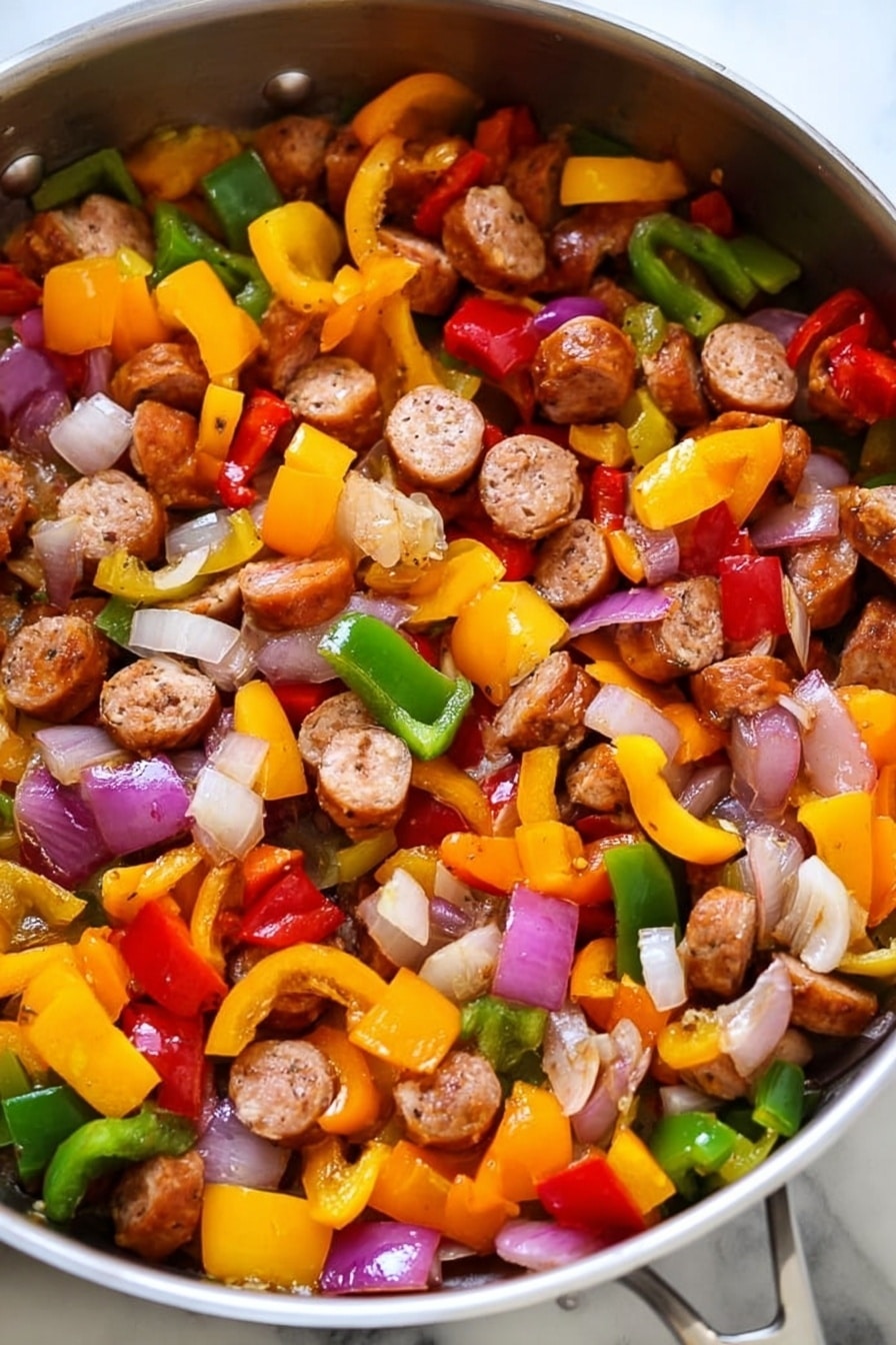 The image shows a pan filled with cooked sausage slices and mixed vegetables. There are three clear layers: the first layer is round sausage pieces that are browned and cooked, scattered evenly throughout the pan. The second layer consists of diced bell peppers in three colors—yellow, red, and green—each piece vibrant and slightly softened from cooking. The third layer includes chopped onions that are translucent with hints of light purple and white, mixed closely with the peppers and sausage. The pan itself is shiny metal on a white marbled texture surface. photo taken with an iphone --ar 2:3 --v 7 - Lightning-Fast Cheesy Three-Pepper Ravioli with Italian Sausage, quick Italian sausage and pepper pasta, easy cheesy ravioli dinner, colorful 3-pepper pasta, weeknight pasta recipe