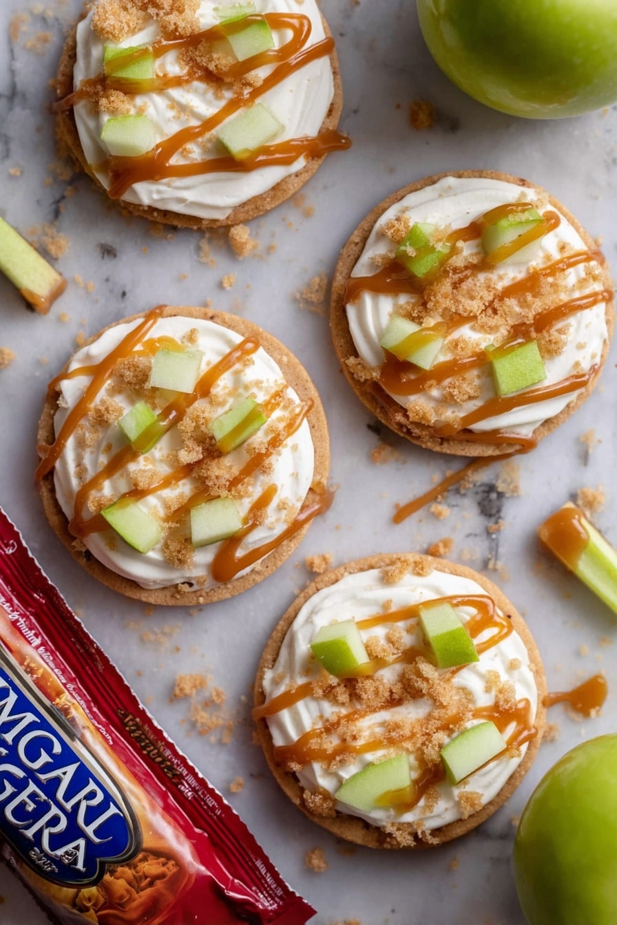 There are four round cookies on a white marbled surface, each cookie topped with a thick swirl of white cream. On top of the cream are small green apple pieces and light brown crumbly bits. Each cookie has thin lines of caramel-colored sauce drizzled over the cream and toppings. A few crumbs are scattered around the cookies. One green apple and a red bag of Imperial Sugar lie near the cookies. In the middle of the cookies is a small stick of green apple with the caramel sauce drizzled on it. photo taken with an iphone --ar 2:3 --v 7 - Caramel Apple Cookies Crumbl Copycat, caramel apple cookie recipe, cinnamon apple cookies, homemade apple caramel dessert, fall cookie recipes