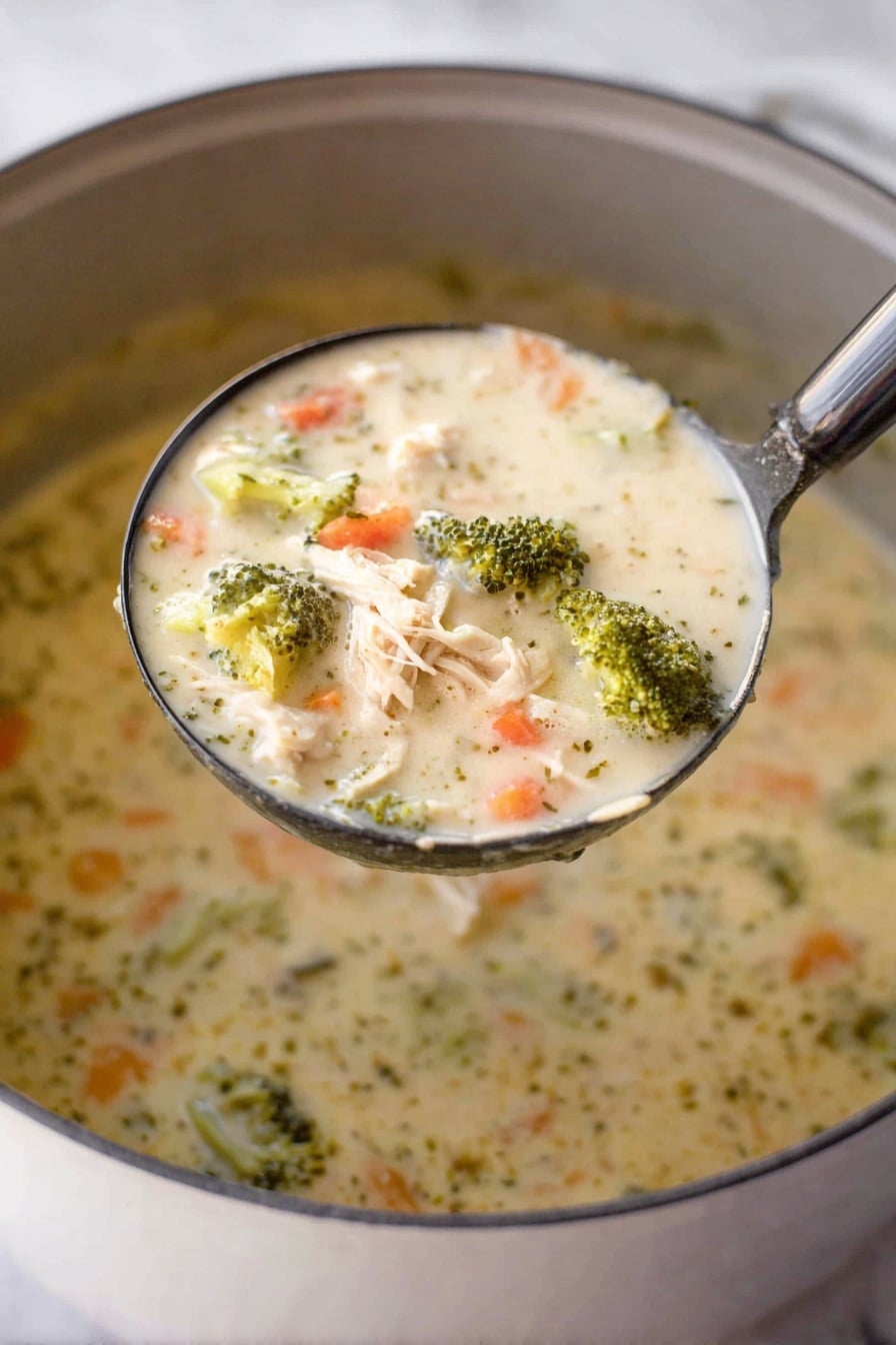 A close-up shot shows a ladle filled with creamy chicken and broccoli soup held above a pot. The soup has a thick, creamy texture with visible chunks of light beige shredded chicken, bright green broccoli florets, and small orange carrot pieces mixed throughout the light cream-colored broth. The surface beneath the pot is a white marbled texture. Photo taken with an iphone --ar 2:3 --v 7 - Creamy Chicken and Broccoli Soup, easy chicken broccoli soup, comforting soup recipes, hearty chicken broccoli dish, healthy creamy soup
