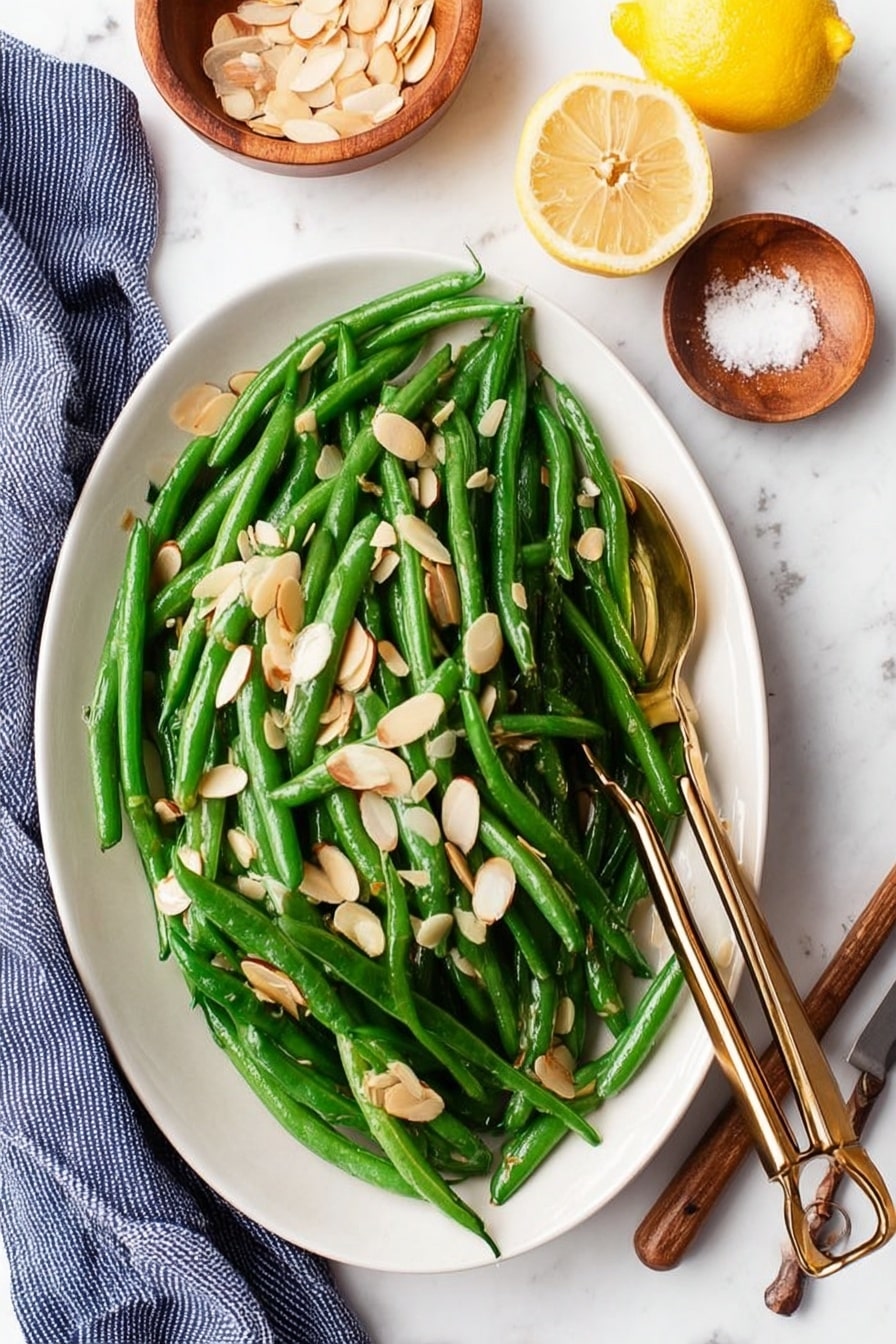 A close-up view of a black cast iron skillet filled with bright green cooked green beans mixed with thin slices of cooked white onions. A light-colored wooden spatula with visible grain rests on top of the green beans, placed in the center of the skillet. The skillet sits on a white marbled surface with a light gray cloth partially visible behind it. To the upper right, there is a wooden spoon holding two halves of a yellow lemon. At the bottom of the image, two small wooden objects are slightly visible. The whole scene has soft, natural light highlighting the fresh textures. photo taken with an iphone --ar 2:3 --v 7 - Easy Green Beans Almondine, green beans almondine, green bean side dish, healthy green bean recipe, quick green bean recipes