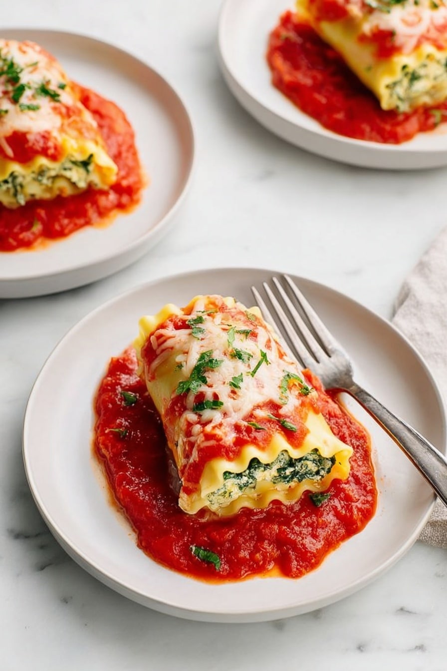 The image shows three white plates on a white marbled surface, each with one piece of rolled lasagna. Each lasagna roll has about three layers of pale yellow pasta with visible green spinach inside. They are topped with melted white cheese and sprinkled with small green herb pieces. The lasagna rolls sit on a bright red tomato sauce that spreads under and around them on the plates. One plate in the front has a silver fork on its right side, partly resting on the plate. The photo is lit brightly, showing clear details and fresh colors. photo taken with an iphone --ar 2:3 --v 7 - Spinach Lasagna Roll-Ups, healthy lasagna roll-ups, easy spinach lasagna, baked spinach roll-ups, creamy ricotta spinach casserole