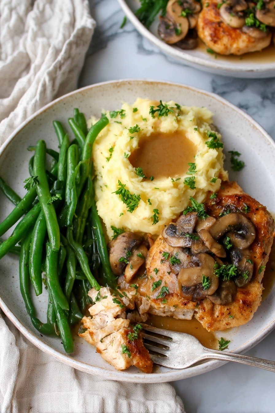 The image shows a white plate with three main parts: bright green cooked green beans placed on the left, a creamy mound of pale yellow mashed potatoes with a small pool of light brown gravy sitting on top in the upper right, and a golden brown cooked chicken piece covered with sliced sautéed mushrooms and chopped green parsley in the bottom right. A fork with a piece of chicken is resting on the edge of the plate, and the plate is set on a white marbled surface with a piece of off-white cloth nearby. Photo taken with an iphone --ar 2:3 --v 7 - Chicken Marsala with Mushrooms and Cream, Chicken Marsala, Mushroom Chicken Marsala, Creamy Chicken Marsala, Easy Chicken Marsala dinner