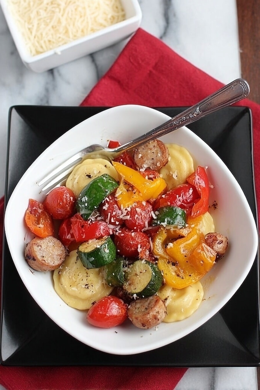 A white square bowl filled with a colorful mix of food sits on a larger black square plate, all placed on a white marbled surface with a red cloth napkin nearby. The bowl contains three round ravioli pieces at the bottom, light yellow in color with a smooth texture. On top of the ravioli are several pieces of sausage, sliced into thick rounds with a browned outer surface, along with large pieces of bell peppers in green, yellow, and red, each showing a slightly glossy and roasted texture. Scattered throughout are bright red cherry tomatoes, some whole, others split, and all glistening slightly. A silver fork rests inside the bowl, angled and leaning toward the right side. Nearby, a white square dish filled with grated cheese is partially visible. The photo taken with an iphone --ar 2:3 --v 7 - Lightning-Fast Cheesy Three-Pepper Ravioli with Italian Sausage, quick Italian sausage and pepper pasta, easy cheesy ravioli dinner, colorful 3-pepper pasta, weeknight pasta recipe