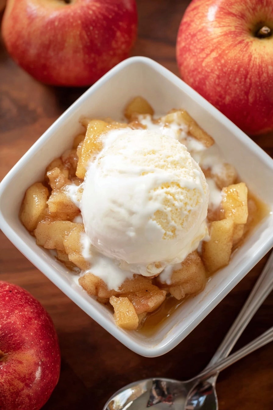 A white square bowl is filled with one layer of soft cooked apple pieces with a light brown color and chunky texture. On top, there is one scoop of creamy white vanilla ice cream that is melting slightly, spreading smooth white cream over the apples. The bowl sits on a wooden surface next to two red apples and a silver spoon. The lighting is soft and natural, highlighting the warm and cool tones of the dessert. photo taken with an iphone --ar 2:3 --v 7 - Apple Brown Betty, Apple Brown Betty dessert, comforting apple crisp, easy fall dessert, traditional apple crumble