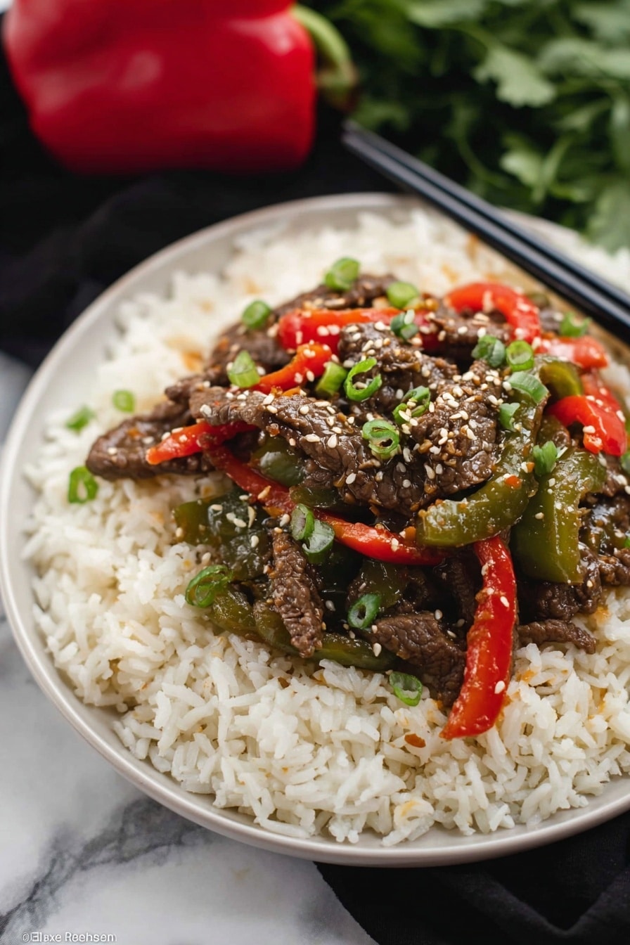 The dish shows three layers on a black plate: the bottom layer is a bed of fluffy white rice with a soft texture, the middle layer has bright green and red cooked bell peppers that look tender and shiny, and the top layer is dark brown strips of cooked beef covered with white sesame seeds and small pieces of green onion scattered on top. The background is a white marbled texture with a pair of dark chopsticks resting near the plate. photo taken with an iphone --ar 2:3 --v 7 - Crockpot Pepper Steak, slow cooker beef dinner, easy crockpot recipes, hearty beef and bell peppers, comfort food slow cooker