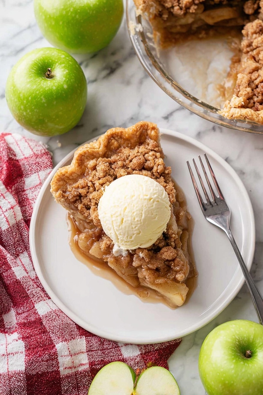 A white plate holds a single slice of apple crumble pie showing three visible layers: a golden brown crinkled crust on the outside edge, a thick middle layer of soft apple pieces coated in sticky brown sugar sauce, and a crumbly cinnamon topping in light and dark brown tones. On top of the pie slice sits a round scoop of creamy off-white vanilla ice cream that is starting to melt slightly. A silver fork lies diagonally on the plate pointing toward the bottom right corner. The plate rests on a white marbled surface surrounded by four whole shiny green apples and one apple cut in half showing pale yellow flesh inside. A red and white checkered cloth sits near the plate's bottom left corner. In the upper right corner, a glass pie dish contains the remaining apple crumble pie with a missing slice. Photo taken with an iphone --ar 2:3 --v 7 - Dutch Apple Pie, apple pie with crumb topping, homemade Dutch apple pie, easy apple pie recipe, best apple pie dessert