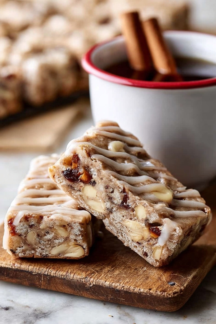 The image shows two triangular bars leaning against each other on a wooden board with a cinnamon stick nearby. Each bar has a thick, light brown base with a slightly crumbly texture, filled with visible chunks of nuts and possibly dried fruit, giving darker brown and creamy white spots inside. The bars are drizzled with a light tan glaze in thin lines across the top and sides. Next to the bars is a white cup with a red rim containing a dark liquid and two cinnamon sticks inside. The background is blurred but shows more bars on a white marbled surface. photo taken with an iphone --ar 2:3 --v 7 - Brown Butter Apple Blondies with Cinnamon Maple Glaze, fall dessert recipes, cozy apple blondies, homemade blondie recipes, apple cinnamon dessert