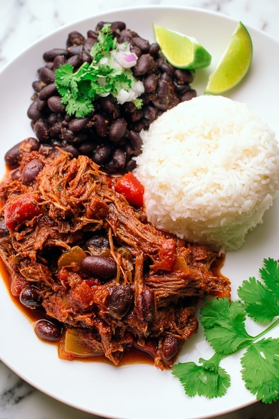A white plate with three main layers: on the top right, a mound of white fluffy rice with a soft texture; on the top left, a scoop of cooked black beans mixed with small onion pieces, topped with a sprig of fresh green cilantro; and covering the bottom half of the plate, a rich, thick reddish-brown stew with shredded meat and chunks of vegetables like olives and red peppers. On the right edge of the plate, a lime wedge adds a touch of bright green. Fresh cilantro leaves lie on the white marbled surface near the plate. Photo taken with an iphone --ar 2:3 --v 7 - Slow Cooker Ropa Vieja, Cuban shredded beef stew, easy Cuban beef recipe, crockpot Ropa Vieja, authentic Cuban stew