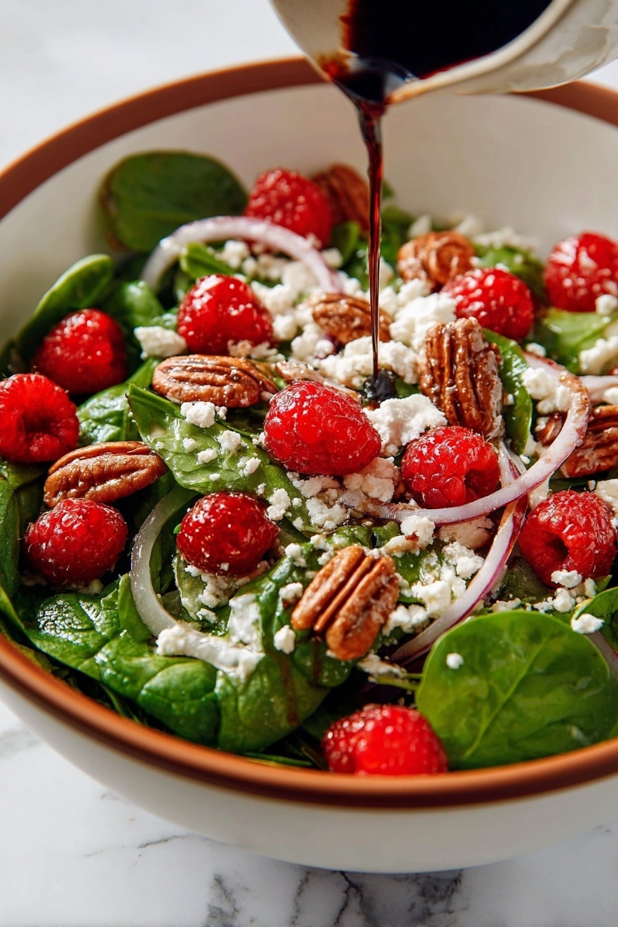 This image shows a fresh salad in a white bowl with a wooden spoon on the side. The salad has several layers and colors: the base is bright green spinach leaves mixed with thin slices of purple onion; scattered on top are red raspberries and brown pecan nuts adding texture; white crumbled goat cheese is spread evenly across the salad, with dark balsamic glaze drizzled over everything, giving a shiny and rich look. The bowl rests on a blue cloth, all placed on a white marbled surface. Photo taken with an iphone --ar 2:3 --v 7 - Spinach Salad with Goat Cheese, Raspberries, and Toasted Pecans,healthy raspberry spinach salad,easy gourmet salads,fresh spinach salad recipes,nutty berry salad