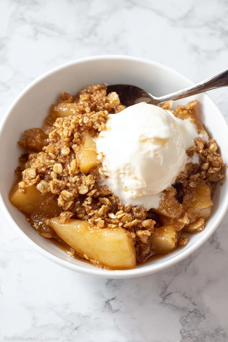 A close-up view of a white bowl filled with a warm apple dessert that has three main layers: a soft layer of sliced cooked apples with a light golden color on the bottom and middle, covered by a thick, sticky caramel sauce that gives a shiny, wet look, and topped with a crumbly, brown oat topping that looks crunchy with small clusters scattered unevenly on top. The dish looks moist and inviting, with the caramel sauce slightly dripping between the apple slices and crumbs. The white bowl sits against a white marbled surface. Photo taken with an iphone --ar 2:3 --v 7 - Healthy Apple Crisp, healthy apple crisp recipe, wholesome apple dessert, gluten-free apple crisp, easy fall dessert