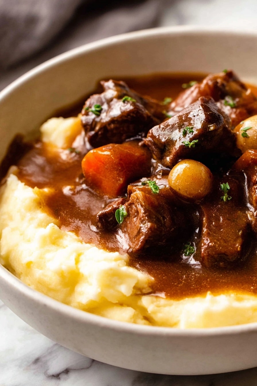 A white bowl filled with two layers: the bottom layer is smooth, creamy mashed potatoes in a light yellow color, and the top layer is a rich, dark brown stew with chunks of tender meat, whole small onions, and thick slices of carrots, all coated in a shiny gravy. The stew slightly spills over the mashed potatoes, garnished with small sprinkles of green herbs. The bowl is placed on a white marbled surface with a folded cloth and a glass of red wine slightly visible in the background along with a detailed old-fashioned spoon in front of the bowl. Photo taken with an iphone --ar 2:3 --v 7 - Beef Bourguignon, Beef Burgundy, classic French beef stew, slow cooker beef stew, hearty beef bourguignon recipe