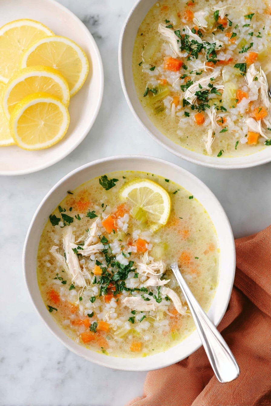 Two white bowls filled with chicken soup placed on a white marbled surface. Each bowl has a light yellow broth with shredded chicken pieces, small diced orange carrots, small green celery pieces, and white rice, topped with chopped green herbs. One bowl shows a silver spoon resting inside the bowl on the right side. A lemon wedge sits on the edge of the front bowl. Next to the bowls, there is a white plate holding several lemon slices. A soft orange cloth napkin lies under the front bowl. Photo taken with an iphone --ar 2:3 --v 7 - Lemon Chicken Rice Soup, healthy lemon chicken soup, easy chicken and rice soup, comforting chicken soup recipes, lemon soup for dinner
