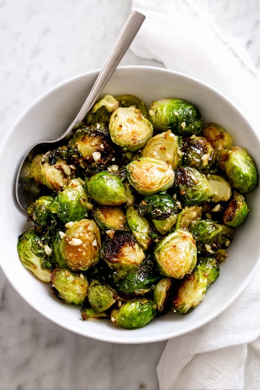 This close-up image shows several roasted Brussels sprouts resting on a white marbled surface. Each Brussels sprout is halved, revealing an inner layer of tightly packed leaves that are light green and yellow with caramelized, dark brown edges from roasting. Some outer layers are slightly charred and crispy, showing darker green and brown colors. Small bits of seasoning or salt are visible on the caramelized tops, adding texture and contrast. The moisture and oil around the sprouts create a slight shine, making the roasted texture stand out. photo taken with an iphone --ar 2:3 --v 7 - Garlic Butter Brussels Sprouts, Brussels Sprouts with Garlic and Butter, Easy Roasted Brussels Sprouts, Healthy Brussels Sprouts Side Dish, flavorful Brussels Sprouts Recipe