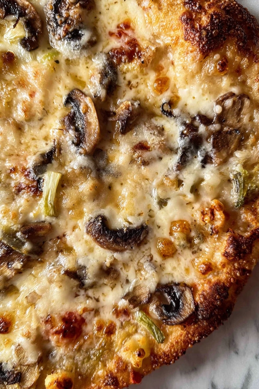 A close-up view of a pizza showing one visible layer with melted cheese covering the surface in creamy white and light golden shades, dotted with browned spots. There are slices of browned mushrooms scattered unevenly across the pizza, adding dark brown and black shapes. Small pieces of slightly green and white vegetables are distributed between the mushrooms and cheese, with some reddish tomato bits peeking through. The edges show a browned crust with some darker burnt spots. The pizza is on a white marbled surface. photo taken with an iphone --ar 2:3 --v 7 - Healthy Chicken Zucchini Bake, healthy chicken zucchini casserole, low-carb zucchini chicken bake, nutritious chicken and vegetable bake, easy healthy chicken recipes