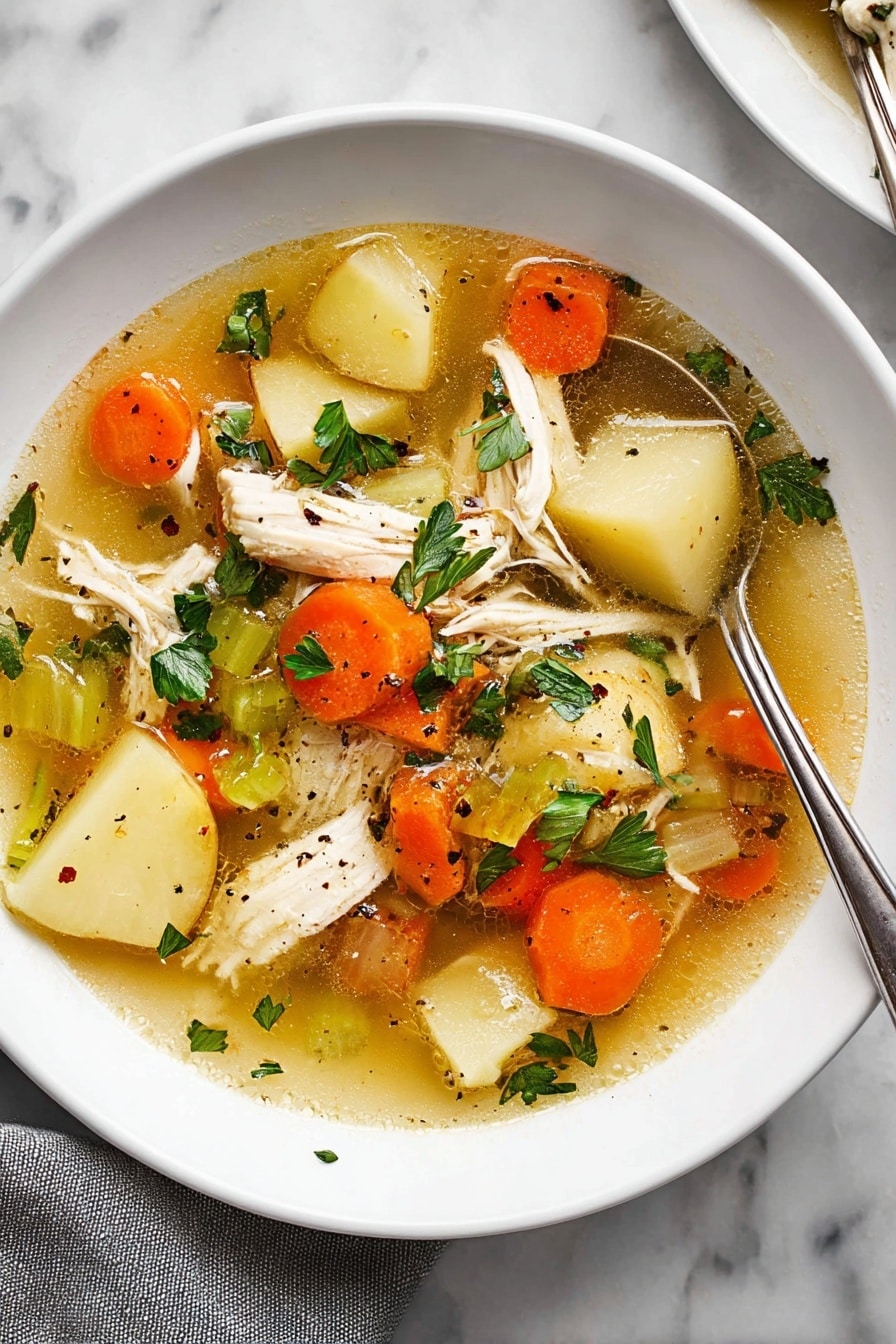The image shows a white plate filled with clear chicken soup that has a golden broth base. Inside the soup, there are several layers: large pieces of white shredded chicken, sliced orange carrots, light beige potato slices, and sections of green celery. Scattered on top are fresh green parsley leaves and small black pepper bits. A silver spoon is partially dipped into the soup on the right side of the plate, resting against the edge. The plate is placed on a white marbled surface, with a grey cloth partially visible at the bottom left corner. photo taken with an iphone --ar 2:3 --v 7 - Ultimate Chicken Soup, comforting chicken soup recipe, hearty chicken soup, easy chicken soup, homemade chicken soup