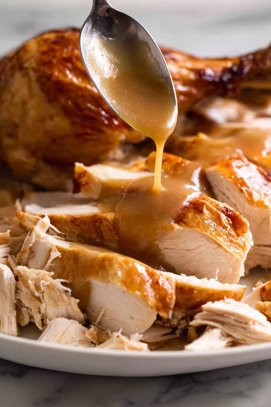 A white plate is filled with sliced roasted chicken with a shiny, golden-brown skin. The chicken is cut into thick pieces, showing tender, white meat inside. At the center, smooth brown gravy is being poured from a spoon, slowly flowing over the chicken slices, adding a glossy layer. Some shredded chicken pieces with light beige tones are placed around the sliced chicken, creating a mix of textures. In the background, part of a roasted chicken drumstick with crispy skin is visible. The entire scene is set on a white marbled surface. Photo taken with an iphone --ar 2:3 --v 7 - KFC-Inspired Homemade Gravy, homemade gravy recipe, quick gravy recipe, savory homemade gravy, easy gravy for mashed potatoes