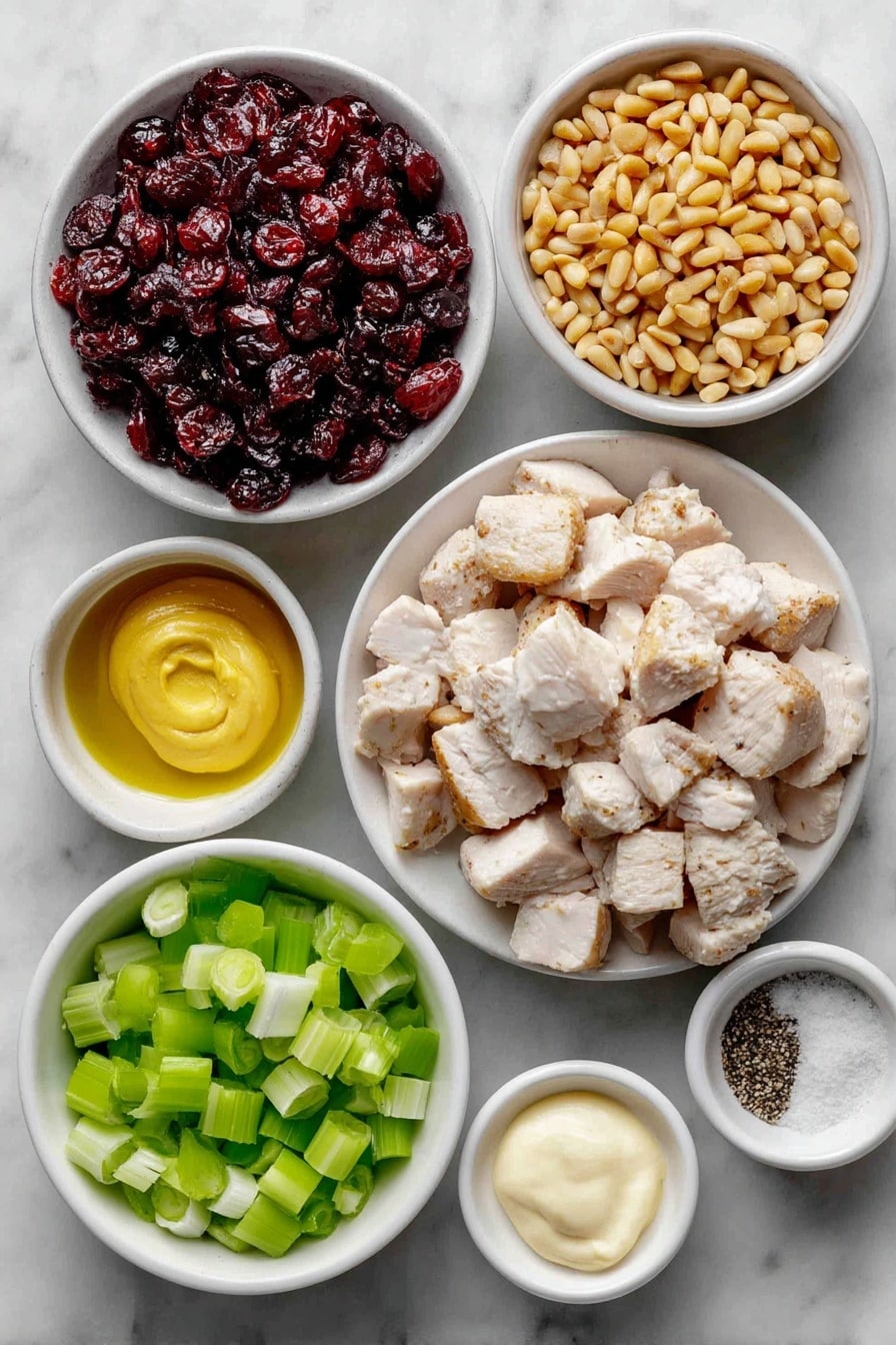 Flat lay of cooked chicken breast chopped into bite-sized pieces, a sliced celery stalk with bright green ribs, thinly sliced green onions showing white and green sections, a small white bowl filled with glossy sweet dried cranberries, a small white bowl containing toasted golden pine nuts, a small white bowl of creamy pale mayonnaise, a small white bowl holding smooth Dijon mustard, a small white bowl with coarse salt crystals, and a small white bowl with freshly ground black pepper placed on a clean white marble surface, soft natural light, photo taken with an iPhone, professional food photography style, fresh ingredients, white ceramic bowls, no bottles, no duplicates, no utensils, no packaging --ar 2:3 --v 7 --p awthu7i m7354615311229779997 - Cranberry Chicken Salad, Cranberry Chicken Salad Recipe, Easy Chicken Salad with Cranberries, Quick Cranberry Chicken Salad, Festive Chicken Salad