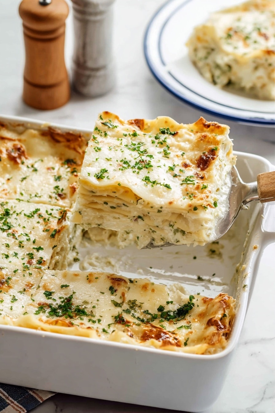 The image shows a white baking dish filled with a six-layer lasagna. Each layer consists of creamy white sauce and pasta sheets with soft, textured edges. The top layer is covered with melted white cheese sprinkled with finely chopped green herbs. The lasagna has a golden-brown crust on some edges. A metal spatula with a wooden handle is placed inside the dish, lifting one square piece from the corner. In the background, a slice of lasagna sits on a white plate with blue trim on a white marbled surface, with a blurred salt and pepper shaker set partly visible. Photo taken with an iphone --ar 2:3 --v 7 - Creamy Chicken Boursin Lasagna, Boursin cheese lasagna, creamy chicken pasta bake, easy chicken lasagna, comforting chicken casserole