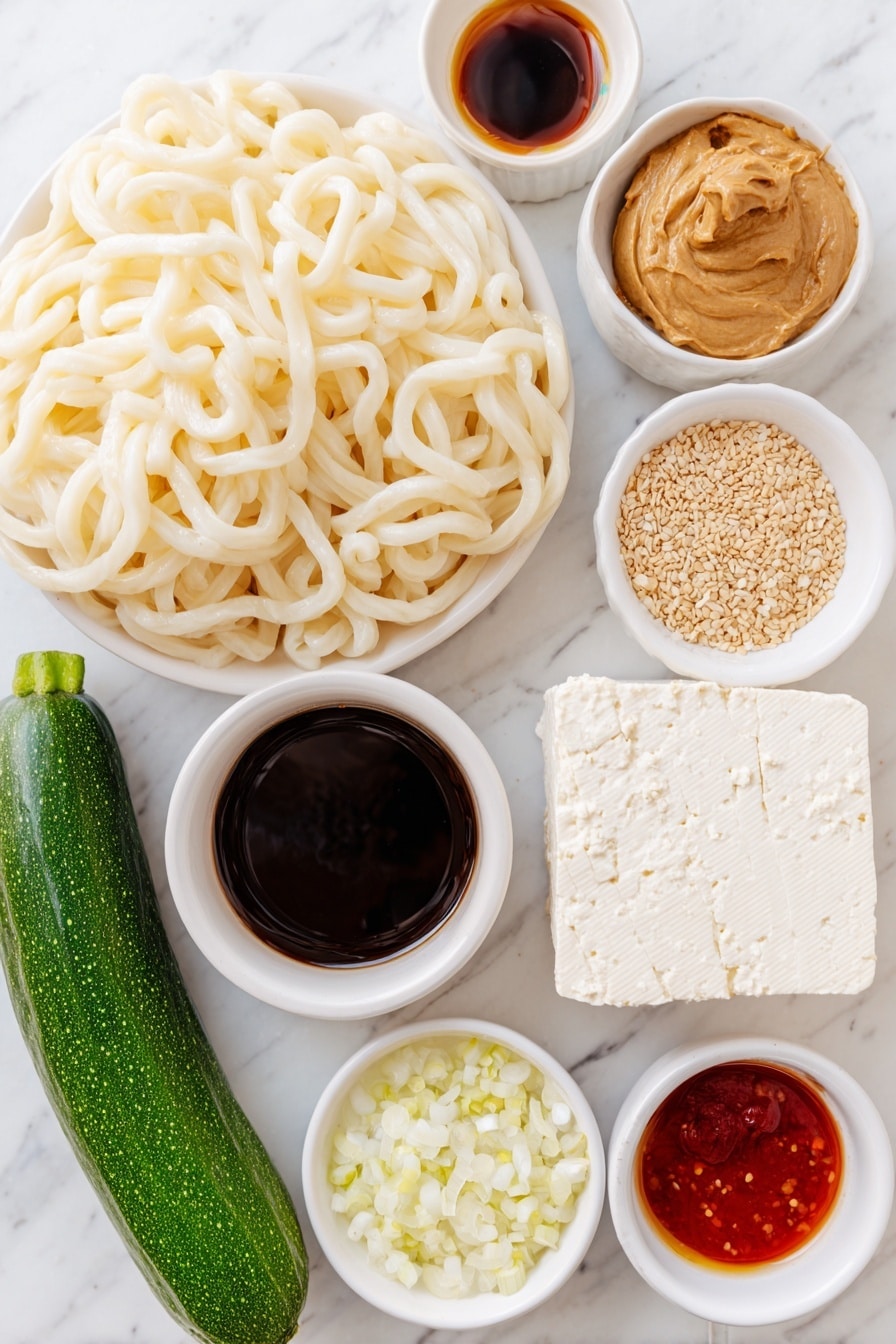 Flat lay of thick cut udon noodles arranged loosely, a whole fresh cucumber with glossy dark green skin, a block of extra firm tofu with a smooth creamy white surface, a small bunch of vibrant green scallions, a small mound of shiny light brown sesame seeds, a small white ceramic bowl of creamy peanut butter, a small white ceramic bowl filled with dark soy sauce, a small white ceramic bowl containing golden toasted sesame oil, a small white ceramic bowl with bright red sriracha, a small white ceramic bowl holding clear rice vinegar, a small white ceramic bowl with finely minced or powdered garlic, a small white ceramic bowl with finely minced or powdered ginger, a small white ceramic bowl of steaming hot water, all placed on a clean white marble surface, soft natural light, photo taken with an iPhone, professional food photography style, fresh ingredients, white ceramic bowls, no bottles, no duplicates, no utensils, no packaging --ar 2:3 --v 7 --p m7354615311229779997 - Peanut Udon Noodles, Thai peanut udon, quick udon noodle recipe, vegan peanut noodles, easy Asian noodle dish