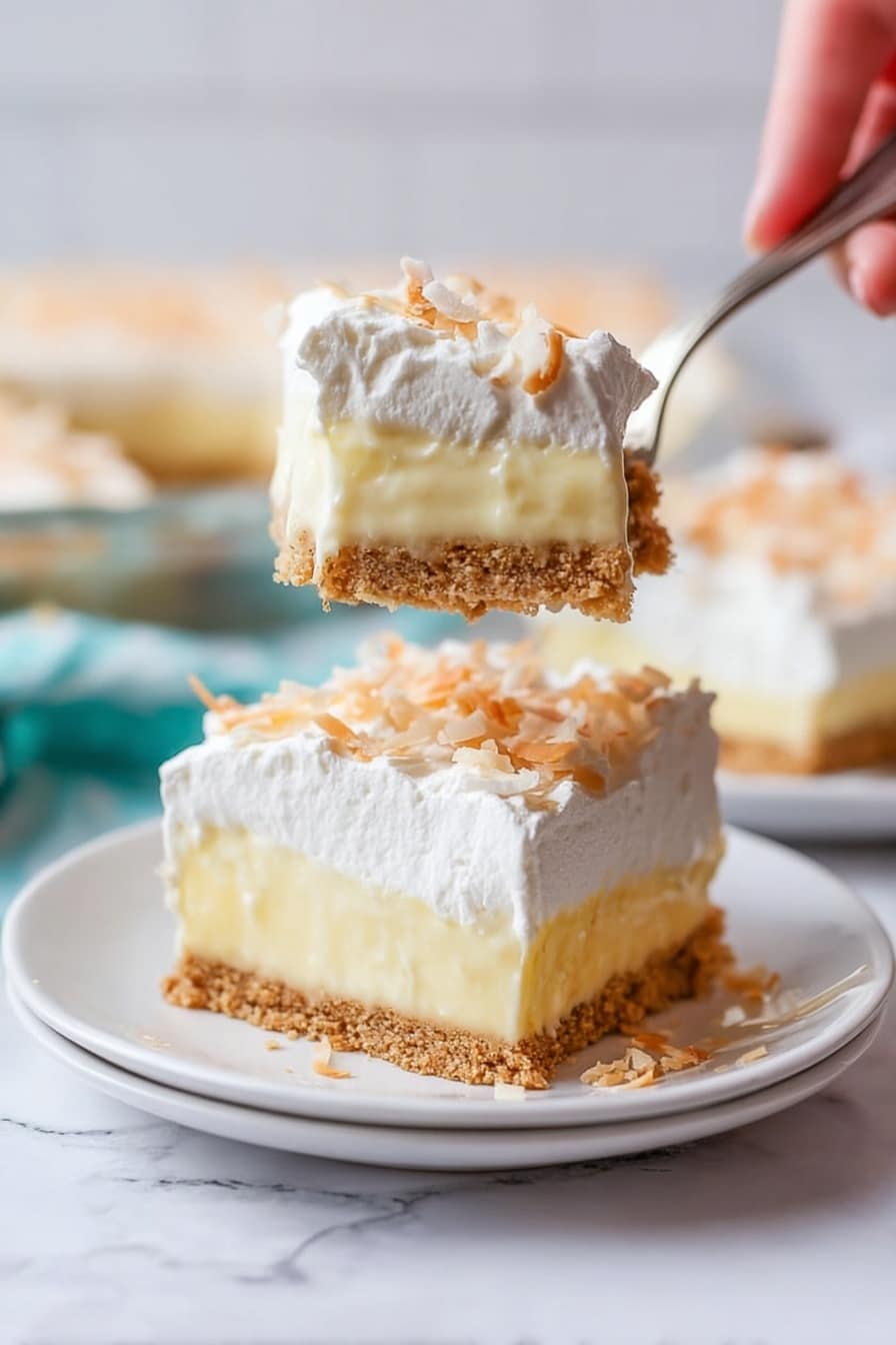 The image shows a slice of a three-layer creamy dessert on a white plate set on a white marbled surface. The bottom layer is a crumbly light brown crust. The middle layer is thick and pale yellow with a smooth texture like pudding. The top layer is white and fluffy, appearing like whipped cream, sprinkled lightly with small toasted shreds that look like coconut. A woman's hand holds a fork above the plate, lifting a piece of the dessert that clearly shows all three layers in a close-up view. The background is softly blurred, with more slices of the dessert visible. photo taken with an iphone --ar 2:3 --v 7 - Coconut Cream Pie, homemade coconut cream pie, classic coconut pie, coconut custard pie, coconut dessert recipe