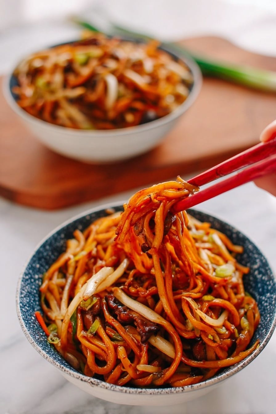 A bowl of noodles sits on a white marbled surface, filled with thick, orange-brown noodles mixed with thin white and light tan vegetables, all coated in a shiny sauce. A woman's hand is holding red chopsticks lifting a tangled cluster of noodles with bits of vegetables and darker brown mushroom-like pieces peeking through. In the background, another bowl filled with the same noodle dish is slightly blurred. The bowls are white with a blue speckled pattern on the outside, and a wooden cutting board with some green onion is faintly seen behind them. photo taken with an iphone --ar 2:3 --v 7 - Restaurant-Style Chicken Lo Mein, Chicken Lo Mein recipe, Chinese chicken noodles, homemade lo mein, easy Chinese stir-fry