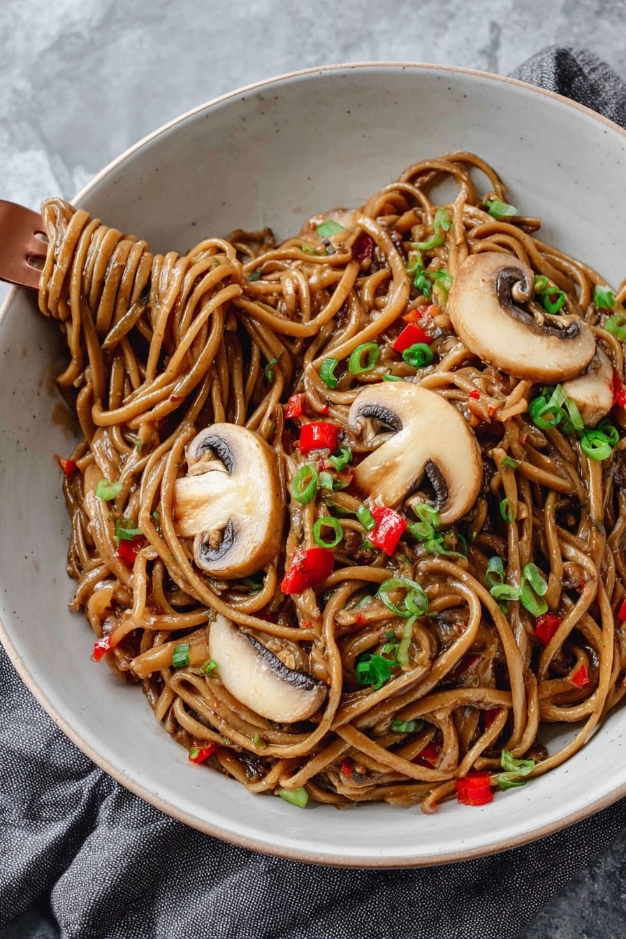 A white bowl is filled with thick noodles coated in a glossy brown sauce, mixed with small pieces of red bell pepper and garnished with finely chopped green onions. On top, there are three large slices of light brown mushrooms with darker edges, laid out neatly. A copper fork is twirling some noodles on the lower left side of the bowl. The bowl sits on a soft grey cloth on a white marbled surface. photo taken with an iphone --ar 2:3 --v 7 - Vegan Kung Pao Pasta with Mushrooms, vegan pasta recipes, Kung Pao pasta recipe, plant-based mushroom pasta, spicy vegan pasta dishes