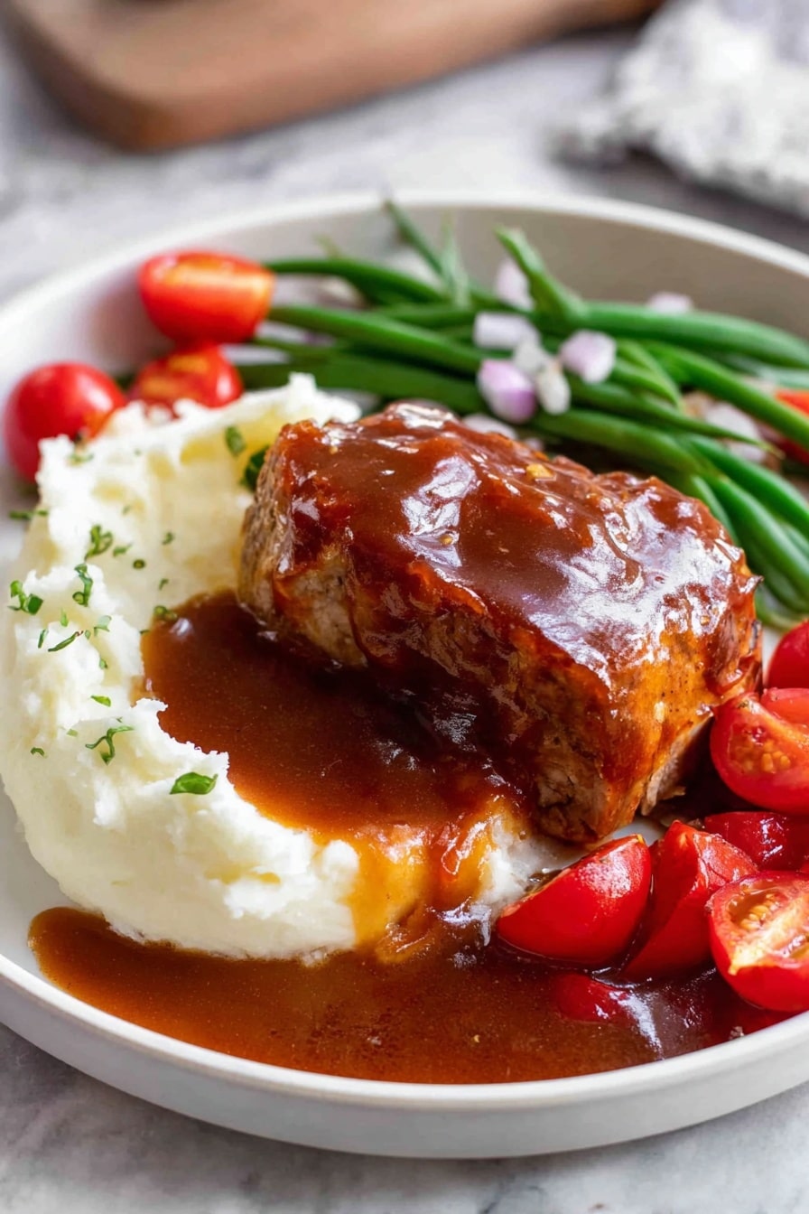 A white plate shows a thick layer of smooth white mashed potatoes on the left side, topped with a glossy brown sauce that pools around the dish. On top of the potatoes sits a piece of cooked meat covered in the same brown sauce, with a slice cut to reveal the inside texture. Behind the meat, there is a row of green beans and bright red cherry tomato halves scattered around, garnished with small pieces of chopped onions. The plate rests on a white marbled surface. Photo taken with an iphone --ar 2:3 --v 7 - Oven Baked BBQ Chicken, Homemade BBQ Sauce, Easy BBQ Chicken Recipe, Juicy baked chicken, Smoked flavor oven baked chicken
