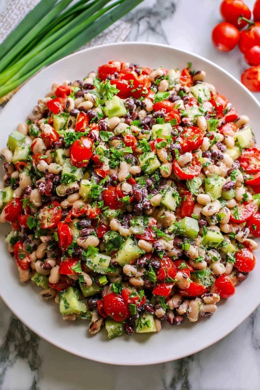 A large white plate holds a mixed bean salad piled high with many colorful ingredients. The salad has three main layers visible: the base layer is made of small, round white and black beans mixed closely together, the middle layer is scattered chopped bright red cherry tomatoes and green cucumber pieces, and the top layer is sprinkled with chopped fresh green herbs that add a fresh, leafy texture. The salad looks fresh and slightly glossy, suggesting a light dressing. The plate sits on a white marbled surface, with green onions and red cherry tomatoes placed nearby for decoration. photo taken with an iphone --ar 2:3 --v 7 - Mediterranean Bean Salad with Feta, Mediterranean Bean Salad, Healthy Bean Salad, Quick Vegetarian Salad, Feta Cheese Salad