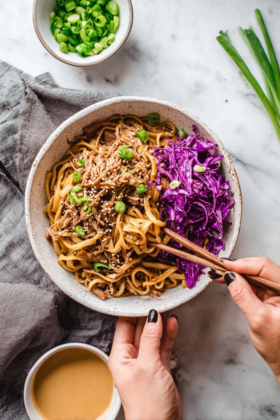 A white speckled bowl filled with a mix of thick, light brown noodles on top, shredded pieces of light brown meat underneath, and bright purple cabbage scattered on the right side and mixed throughout. Light green sliced scallions are sprinkled on top along with small white sesame seeds. A woman's hand holds the bowl from the bottom, while another woman's hand with dark nail polish uses wooden chopsticks to pick up some purple cabbage from the edge of the bowl. Nearby are two small white bowls, one with chopped green scallions and the other with a creamy light brown sauce. The setting is on a white marbled surface with a gray cloth under the bowl, and some scallions lie on the top right side. Photo taken with an iphone --ar 2:3 --v 7 - Thai Peanut Chicken Noodles, Thai chicken noodle recipe, peanut sauce noodles, quick Thai chicken dinner, easy Asian noodle recipe