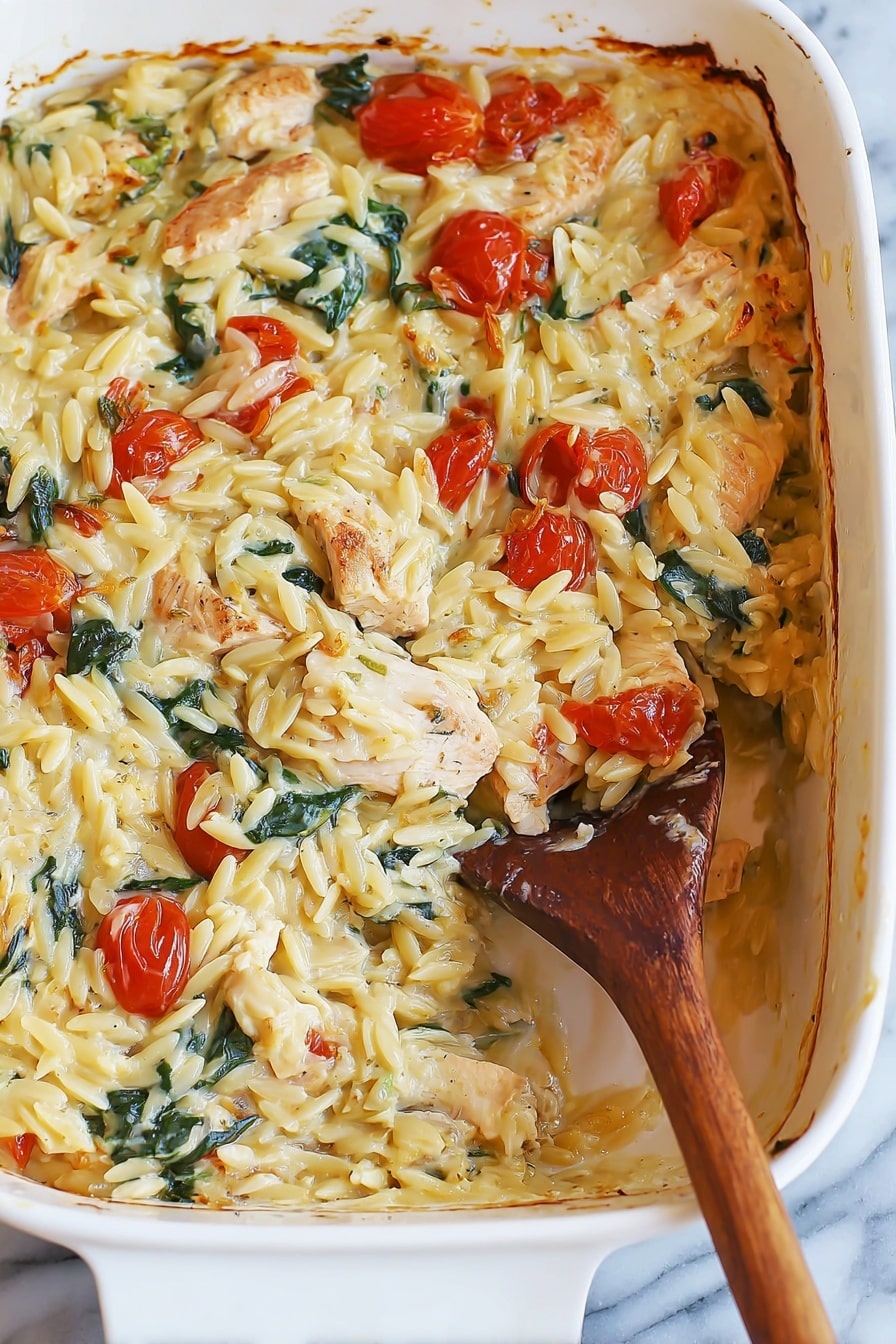 A white baking dish filled with a creamy baked pasta dish, showing about two layers with a scoop taken out from the bottom right side. The top layer has creamy, yellowish orzo pasta mixed with small roasted cherry tomatoes, chunks of light brown cooked chicken pieces, and green spinach leaves, all coated in a creamy sauce. The sides of the dish show some baked brown edges where the sauce has slightly caramelized. A wooden spoon with a long handle is inside the dish, partially covered in the pasta mixture. The dish is placed on a white marbled surface. Photo taken with an iphone --ar 2:3 --v 7 - Creamy Chicken Orzo Bake, Creamy Chicken Orzo, Chicken Orzo casserole, baked chicken and orzo, easy creamy chicken bake