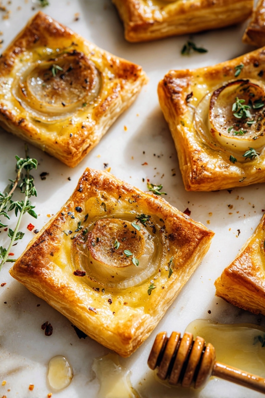 Several square puff pastry tarts are placed on a white marbled surface. Each tart has three main layers: a golden-brown crispy pastry base, a lighter yellow layer of melted cheese, and a thin, translucent round slice of cooked onion in the center. The onion slices have a slightly caramelized texture with some darker, browned edges. Small green fresh herb leaves, likely thyme, are scattered on top, along with a sprinkling of black pepper and red chili flakes. A honey dipper with some honey spilled near the tarts is visible on the right side of the image, adding a sticky shine to the scene. The light creates soft shadows that highlight the flaky texture of the pastry and the shine on the onions. Photo taken with an iphone --ar 2:3 --v 7 - Upside-Down Onion Gruyere Tarts, savory onion tart, easy onion tart recipe, caramelized onion tart, gourmet puff pastry appetizer