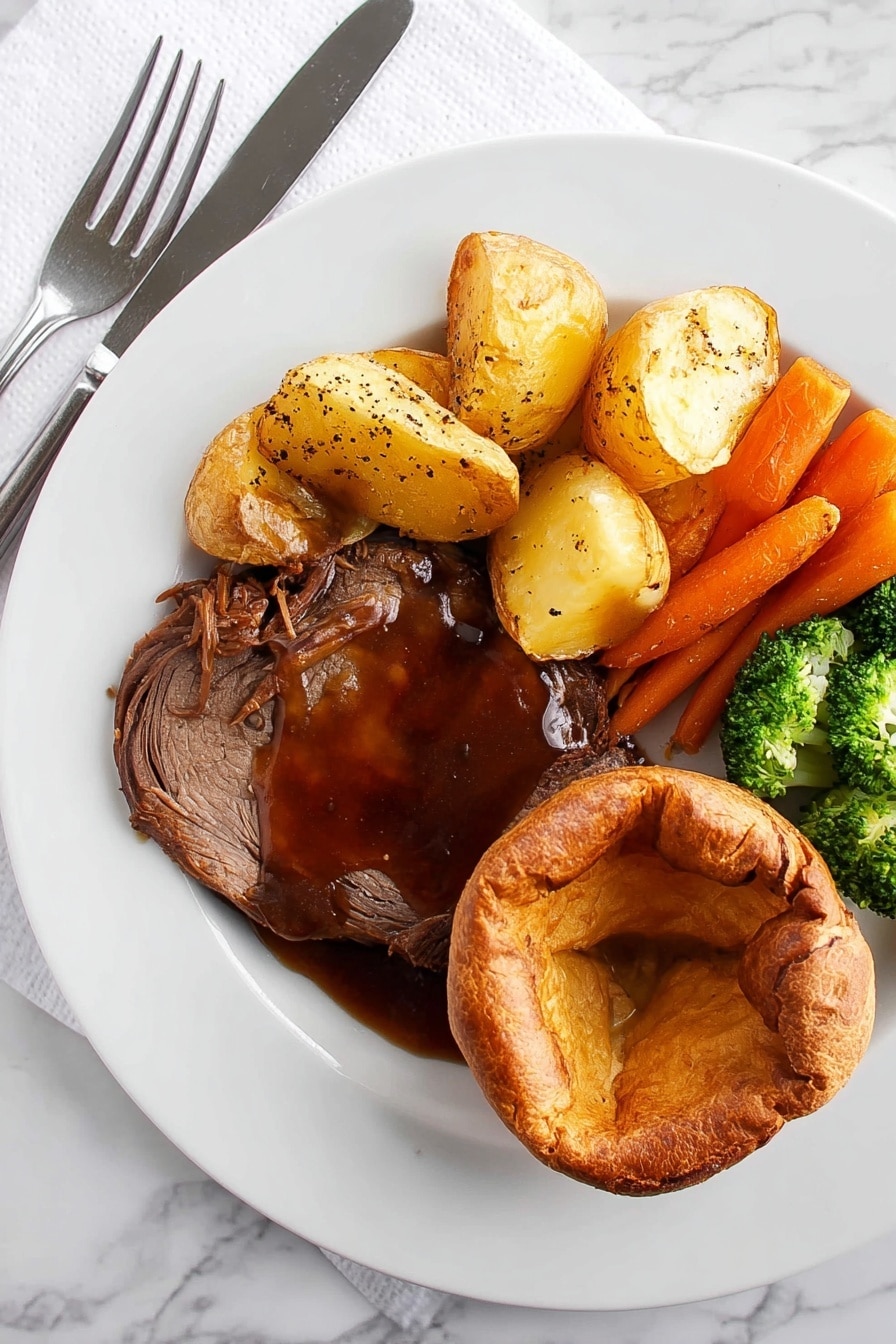 A white plate on a white marbled surface holds a meal with four parts. On the bottom right is a golden brown round Yorkshire pudding with a soft, slightly folded center. Next to it on the left is a thick slice of dark brown roast meat covered in rich, shiny brown gravy sprinkled with coarse black pepper. Above the meat are several light golden roast potatoes with a crispy surface. To the left of the potatoes is a mix of bright orange whole baby carrots and green broccoli florets with a slight shine, showing they are cooked but still fresh. A knife and fork rest on the left side of the plate on a white napkin. Photo taken with an iphone --ar 2:3 --v 7 - Crispy Yorkshire Pudding, Yorkshire Pudding recipe, British side dish, crispy roast side, homemade Yorkshire pudding