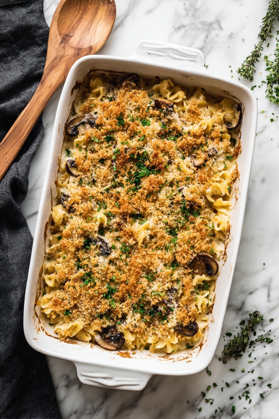 The image shows a white bowl filled with a baked pasta dish consisting of three layers. The bottom layer is light beige penne pasta mixed with cooked dark green spinach. The middle layer reveals slices of browned mushrooms that sit on top of the pasta and spinach mix. The top layer is a golden-brown crispy breadcrumb topping, sprinkled unevenly with some light green herbs for garnish. A silver fork rests on the right side of the bowl. In the background, there is a white baking dish containing the same layered pasta, with a wooden spoon partially submerged in it. The scene is set on a white marbled surface, providing a clean and bright contrast to the dish. Photo taken with an iphone --ar 2:3 --v 7 - Creamy Mushroom Kale Pasta Bake, mushroom kale pasta casserole, easy veggie pasta bake, comforting mushroom pasta dish, healthy kale pasta recipes