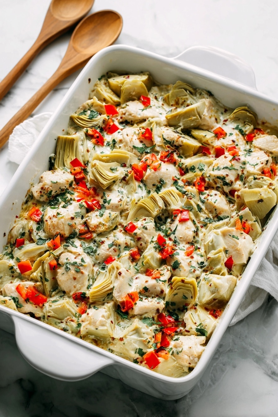 A white rectangular baking dish filled with a layered mix of creamy white sauce, pieces of light beige cooked chicken, and quartered pale green artichoke hearts. The dish is sprinkled with small, bright red bell pepper pieces and finely chopped dark green herbs, creating a colorful contrast. The textures range from creamy sauce to tender chunks of chicken and soft artichokes, all blended evenly across the dish. The dish sits on a white marbled surface with two wooden spoons with white handles placed behind it. Photo taken with an iphone --ar 2:3 --v 7 - Spinach Artichoke Chicken Bake, chicken spinach artichoke bake, baked chicken with spinach and artichokes, easy chicken bake recipes, creamy vegetable chicken dish