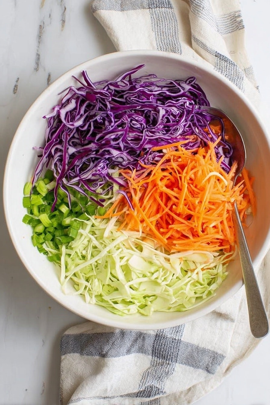 A white bowl on a white marbled surface holds four distinct layers of fresh, thinly shredded vegetables arranged side by side. On the left is shredded purple cabbage with a few green pieces mixed in. To its right is bright orange shredded carrot, slightly overlapping some pieces of purple cabbage. Below the cabbage, finely chopped green onions form the third layer, and next to them, on the bottom right, is a pile of thinly shredded light green cabbage. A silver spoon lies on the surface near the bowl, and a white cloth with gray stripes is partially visible under the bowl. Photo taken with an iphone --ar 2:3 --v 7 - Southern Collard Greens, Collard Greens Recipe, Southern Greens, Soul-Warming Collard Greens, Easy Collard Greens