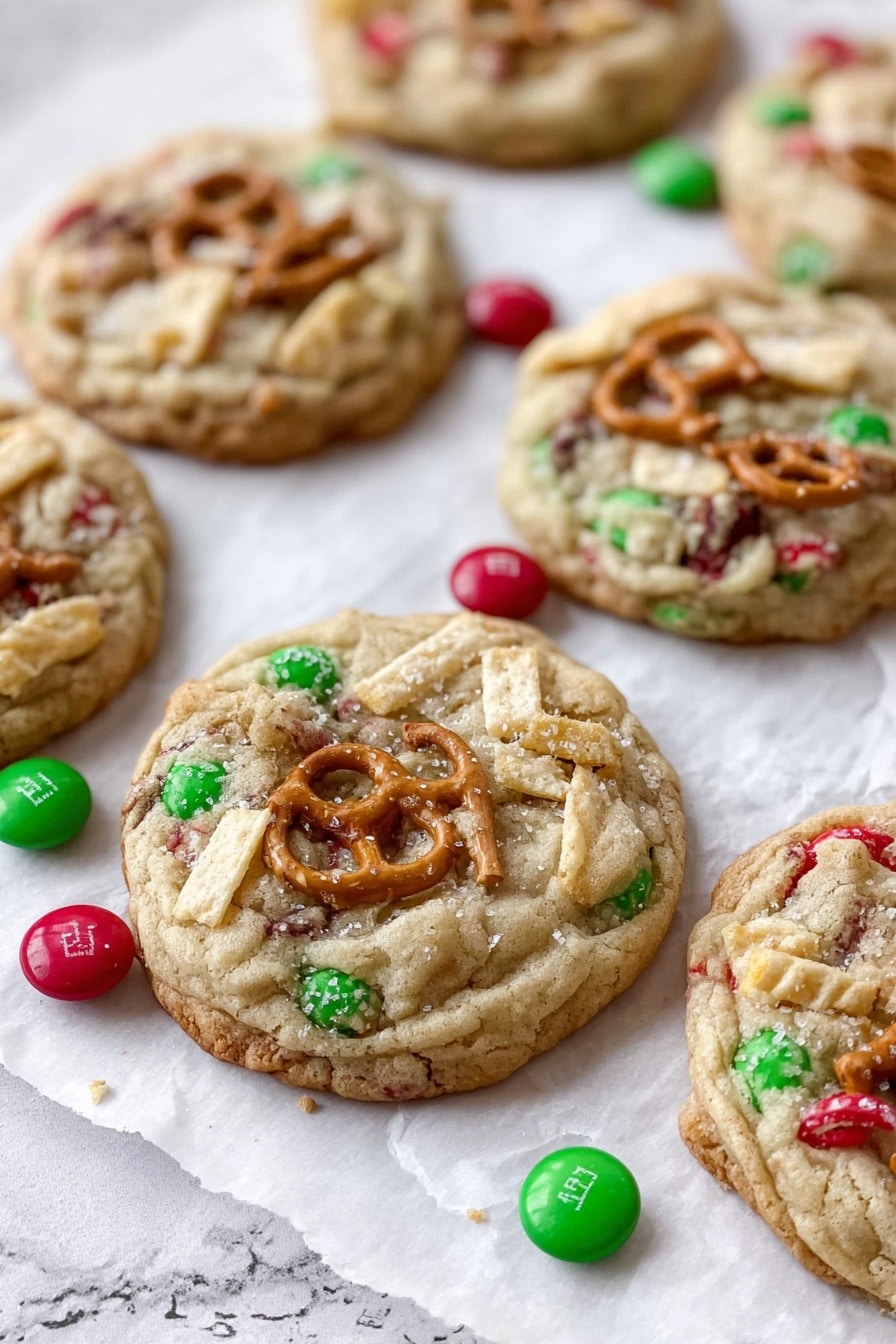 The image shows seven thick cookies laid on white parchment paper over a white marbled surface. Each cookie is light brown and chunky with three main visible layers: the soft dough base, scattered red and green candy pieces embedded inside, and crunchy pretzel pieces along with ridged potato chip bits placed on top. Some loose red and green candies surround the cookies. The texture of the cookies appears soft and a little crumbly with the pretzels and chips adding a crisp contrast. Photo taken with an iphone --ar 2:3 --v 7 - Santa's Trash Cookies, Trash Cookies Recipe, Holiday Cookie Ideas, Easy Cookie Recipes, Christmas Party Cookies