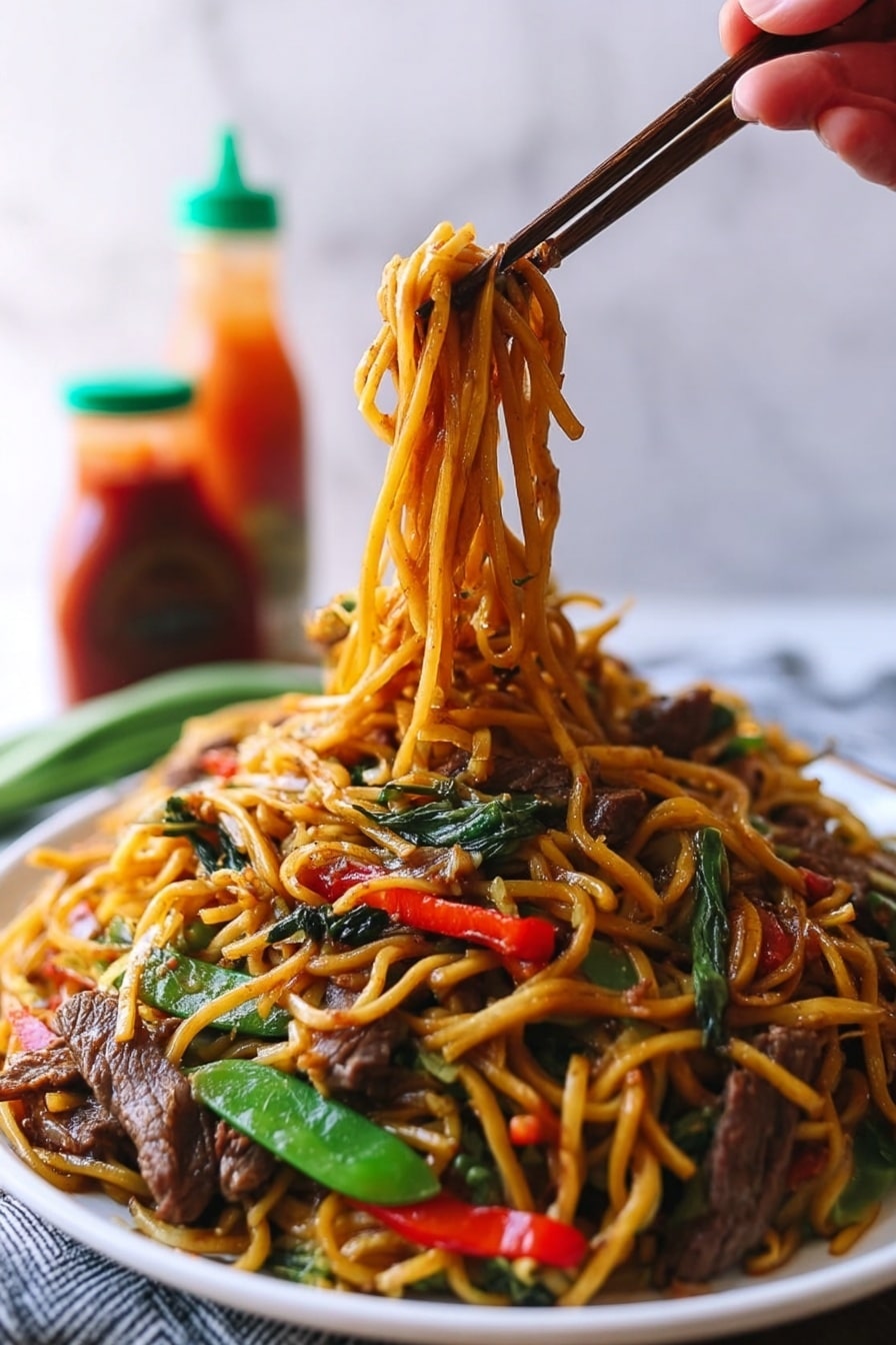 A large white plate holds a colorful stir-fry noodle dish with multiple layers. The bottom layer is long, yellow-brown noodles, glossy from sauce and slightly twisted. Mixed into the noodles are bright green snap peas and long, thin red bell pepper slices adding color contrast. Thin strips of cooked brown beef are scattered evenly on top, along with thin white strands of bean sprouts providing texture. The dish sits on a white marbled surface with blurred background that includes a blue and white bowl and bottles of sauce. photo taken with an iphone --ar 2:3 --v 7 - Beef Lo Mein Stir-Fry, Beef Lo Mein recipe, Chinese beef stir-fry, easy lo mein noodles, flavorful stir-fry dishes