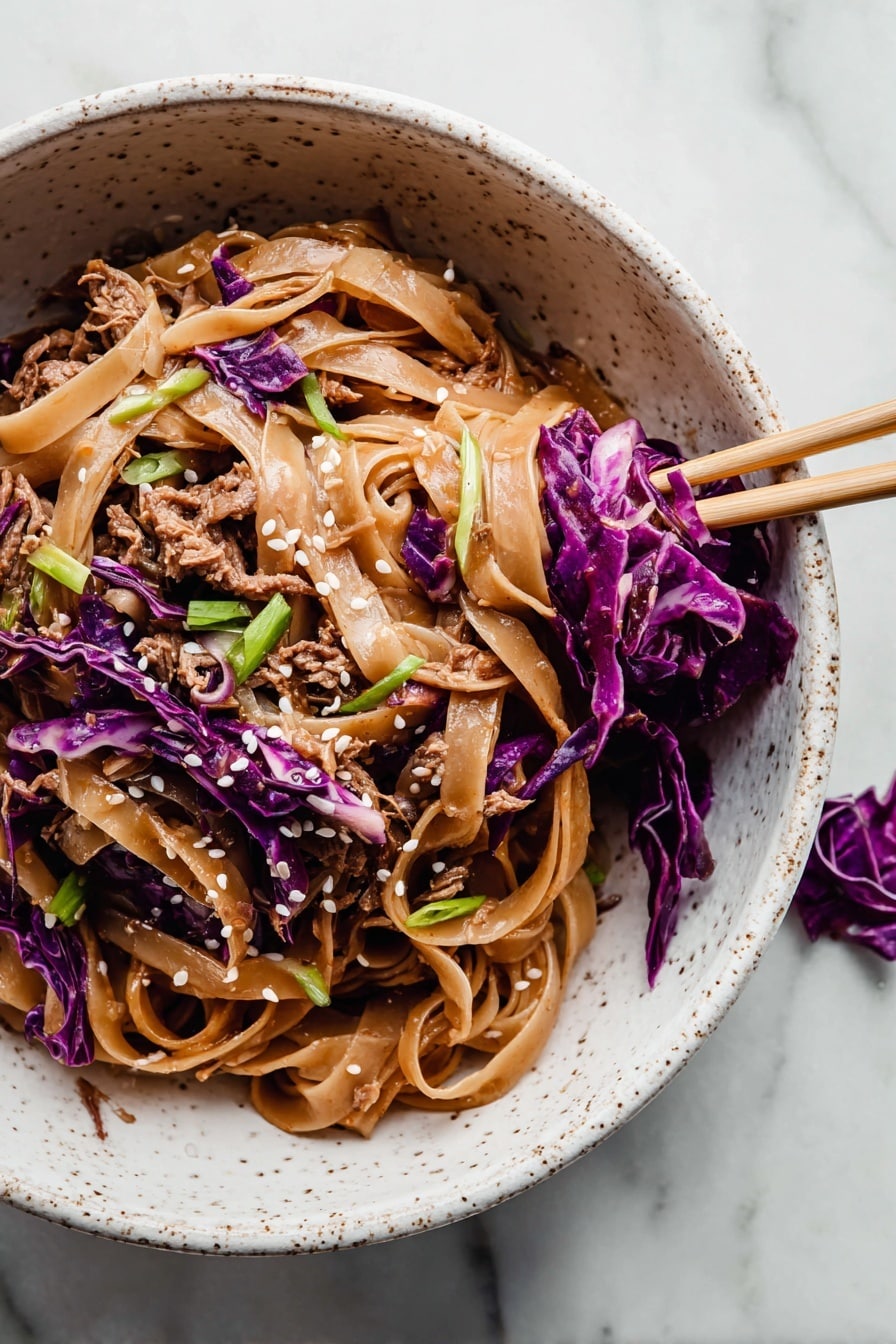 The image shows a white speckled bowl filled with a noodle dish. The bottom layer is made of wide, flat, light brown noodles coated in sauce. Mixed in and on top are shredded pieces of brown cooked meat and thin strips of bright purple cabbage, adding color contrast. Scattered over the dish are small white sesame seeds and green sliced scallions for garnish. A pair of chopsticks rests inside the bowl on the right side, holding some purple cabbage and noodles. The bowl is placed on a surface with a white marbled texture, and a small piece of purple cabbage is nearby. photo taken with an iphone --ar 2:3 --v 7 - Thai Peanut Chicken Noodles, Thai chicken noodle recipe, peanut sauce noodles, quick Thai chicken dinner, easy Asian noodle recipe