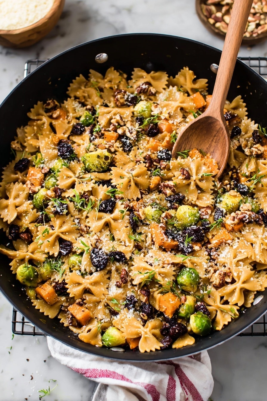 A large black pot filled with a colorful mix of farfalle pasta and small pieces of roasted orange sweet potatoes spread all over. Bright green Brussels sprouts cut in halves and small dark purple dried berries are scattered inside. There are bits of chopped pecans and a light sprinkle of grated cheese on top, with little green herb leaves spread around. In the pot, a wooden spoon rests on the food, and the scene is set on a white marbled surface, with some pecans and a small bowl of grated cheese nearby. A white cloth with a red stripe is partially visible next to the pot. Photo taken with an iphone --ar 2:3 --v 7 - Brussels Sprouts Pasta with Brown Butter, Brussels sprouts pasta, fall pasta recipes, cozy vegetable pasta, caramelized Brussels sprouts recipes
