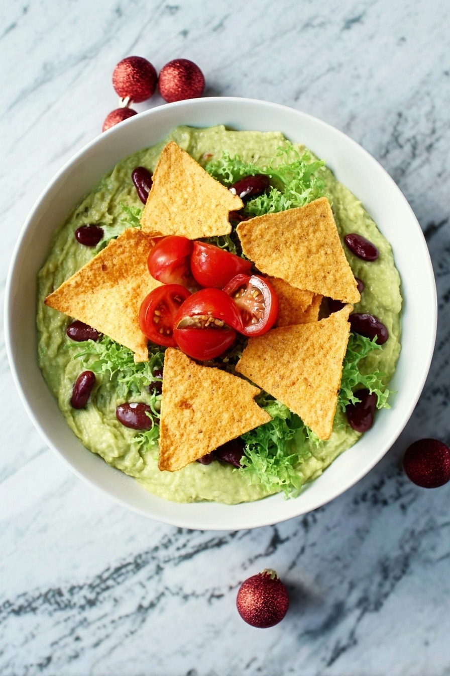 A white bowl filled with a creamy green guacamole base topped by several crispy golden tortilla chips placed in the center. Around the chips, there are bright red cherry tomato halves, fresh green lettuce leaves, and small dark red kidney beans scattered. The bowl is set on a white marbled surface. photo taken with an iphone --ar 2:3 --v 7 - Festive Guacamole with Pomegranate & Tomatoes, holiday guacamole recipe, easy party dip, colorful fruit guacamole, quick festive appetizer
