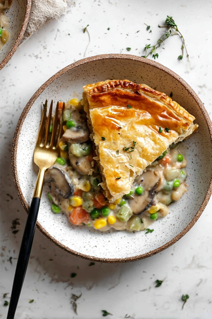 The dish shows one slice of golden brown pastry with a shiny and slightly cracked top crust, placed on top of a creamy mixture with visible layers of light green celery, orange carrot pieces, yellow corn, green peas, white beans, and brown mushrooms. The mix is thick and creamy with small bits of herbs sprinkled on top. The food is served in a white bowl with speckled details, alongside a black and gold fork resting inside the bowl on the left side. The background is a white marbled surface with scattered small green herbs. Photo taken with an iphone --ar 2:3 --v 7 - Creamy Vegetable Pot Pie, vegetarian pot pie, easy vegetable pot pie, comforting veggie dinner, healthy vegetable pie