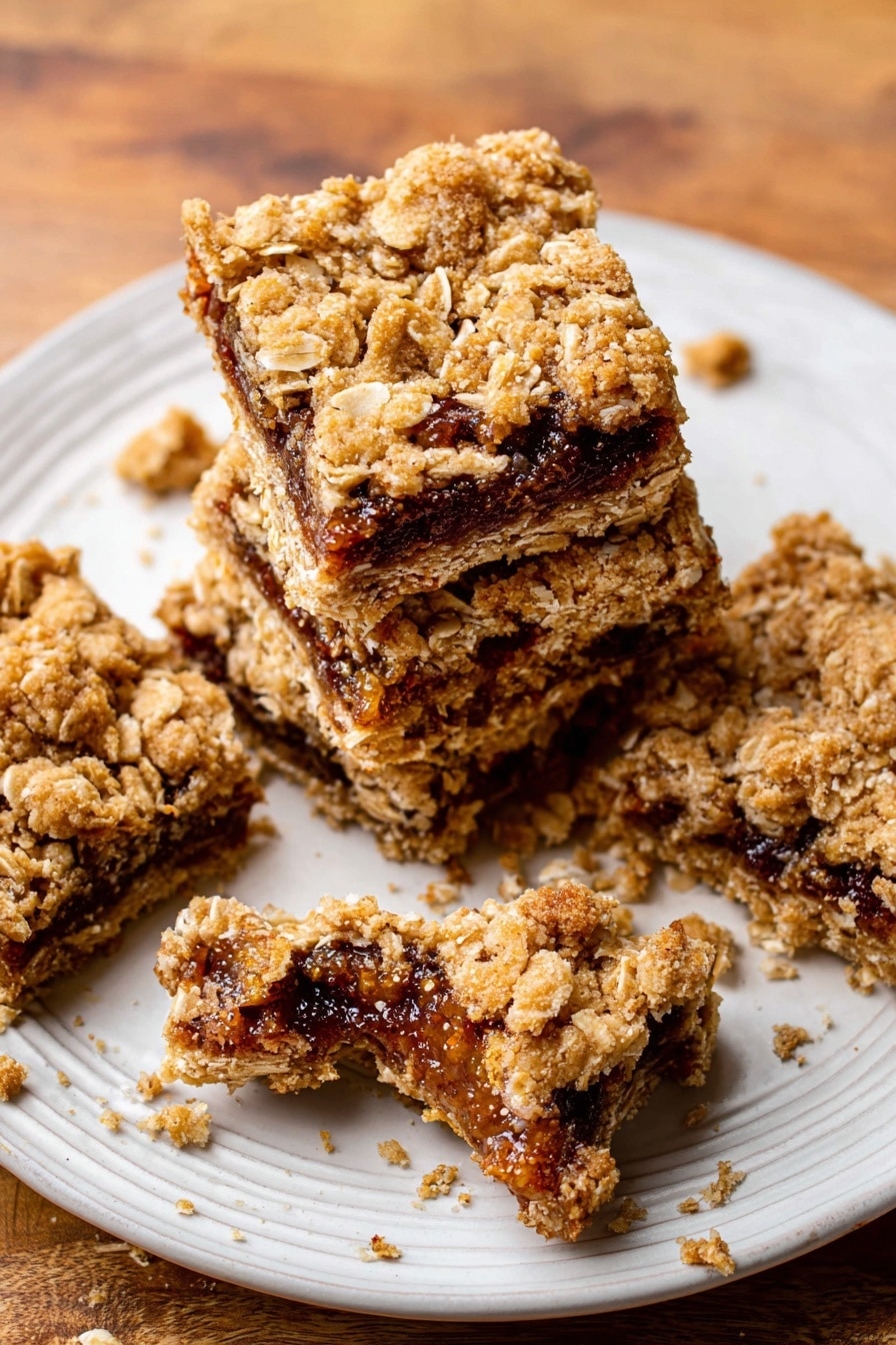 The image shows four oat bars stacked slightly on each other on a white plate with a textured edge. Each oat bar has two visible layers: the top and bottom layers are golden brown with a crumbly texture mixed with oat flakes, and the middle layer is a dark brown fig filling with visible seeds and a sticky look. One oat bar on the plate is broken in half, revealing the thick filling inside. There are crumbs scattered on the plate and around it on a wooden surface. Photo taken with an iphone --ar 2:3 --v 7 - Homemade Oatmeal Fig Bars, healthy fig bar recipe, easy oatmeal bar recipe, natural fig bars, wholesome snack bars
