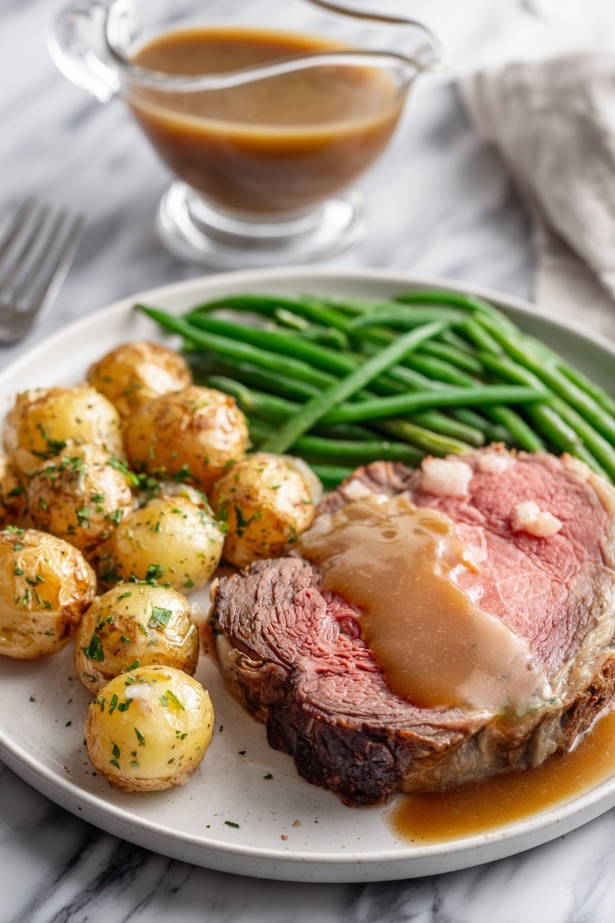 A white plate on a white marbled surface holds a meal with three main parts: a thick, medium-rare roast beef slice with a pink center and browned edges, topped with brown gravy that also pools around it; next to it, a pile of roasted small potatoes with golden brown skins sprinkled with green herbs; and a bunch of bright green cooked green beans laid neatly beside the potatoes. In the background, there is a clear glass gravy boat filled with brown gravy on the white marbled surface. photo taken with an iphone --ar 2:3 --v 7 - Garlic Herb Butter Prime Rib, prime rib roast with garlic and herbs, how to cook perfect prime rib, easy prime rib recipes, juicy prime rib tips