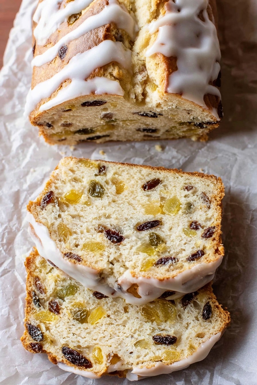 The image shows a loaf of sweet bread with a golden-brown top covered with white icing drizzled over it. The bread is sliced into three pieces, revealing a soft, light beige inside filled with bits of dark raisins and light yellow fruit pieces evenly spread throughout. The bread sits on crumpled parchment paper placed on a white marbled surface, and the slices have a slightly rough texture with visible fruit chunks inside. The crust looks thin and slightly shiny beneath the icing. Photo taken with an iphone --ar 2:3 --v 7 - German Stollen Bread, festive German bread, Christmas fruit bread, traditional German Stollen, holiday bread recipes